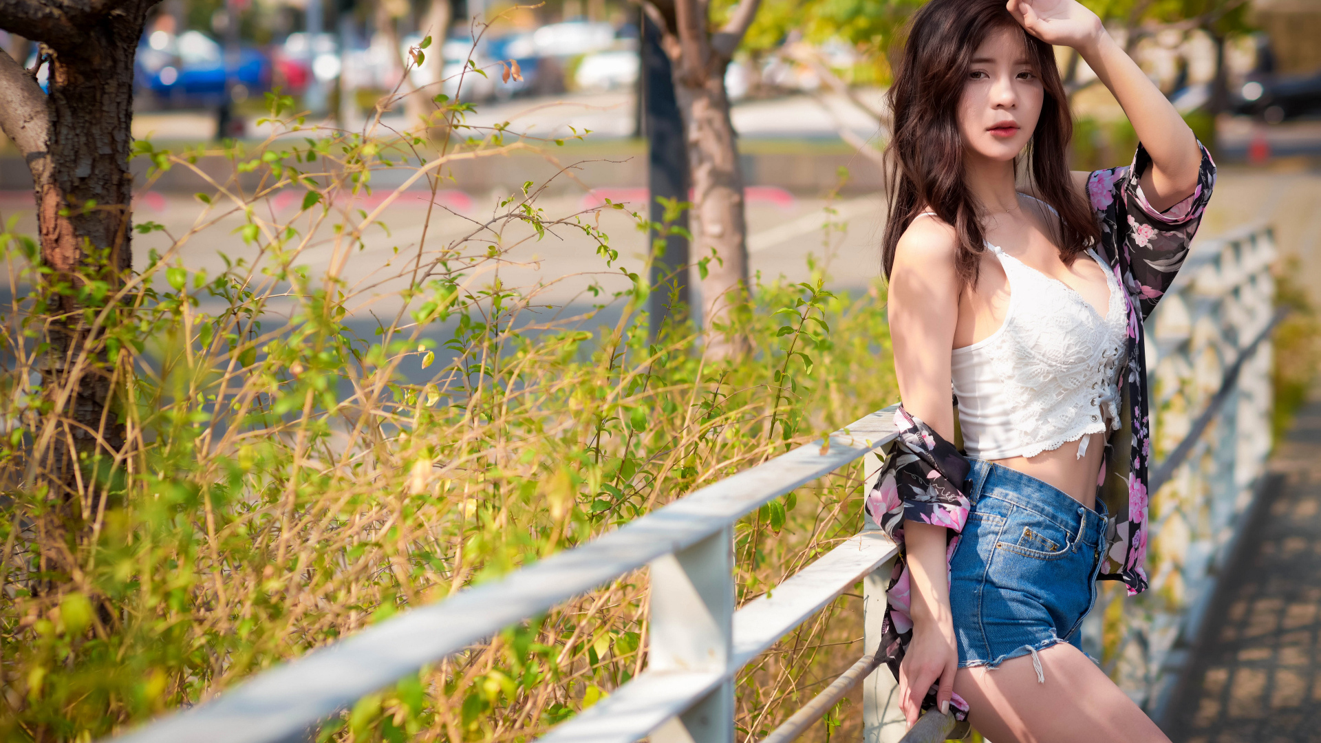 Молодая азиатка в синих шортах стоит у забора