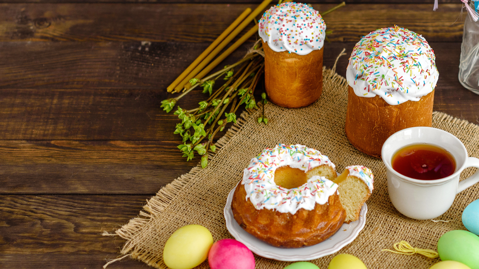 Сладкие пасхальные куличи на столе с чаем и крашеными яйцами