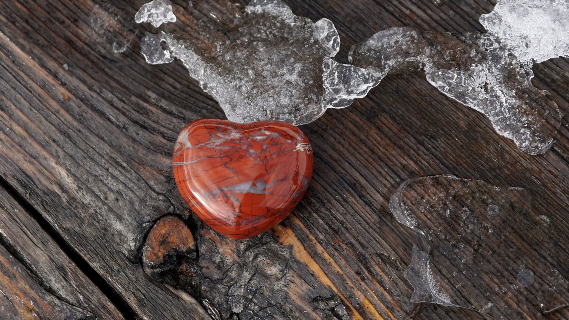 Сердце из камня на деревянной лавке с тающим снегом