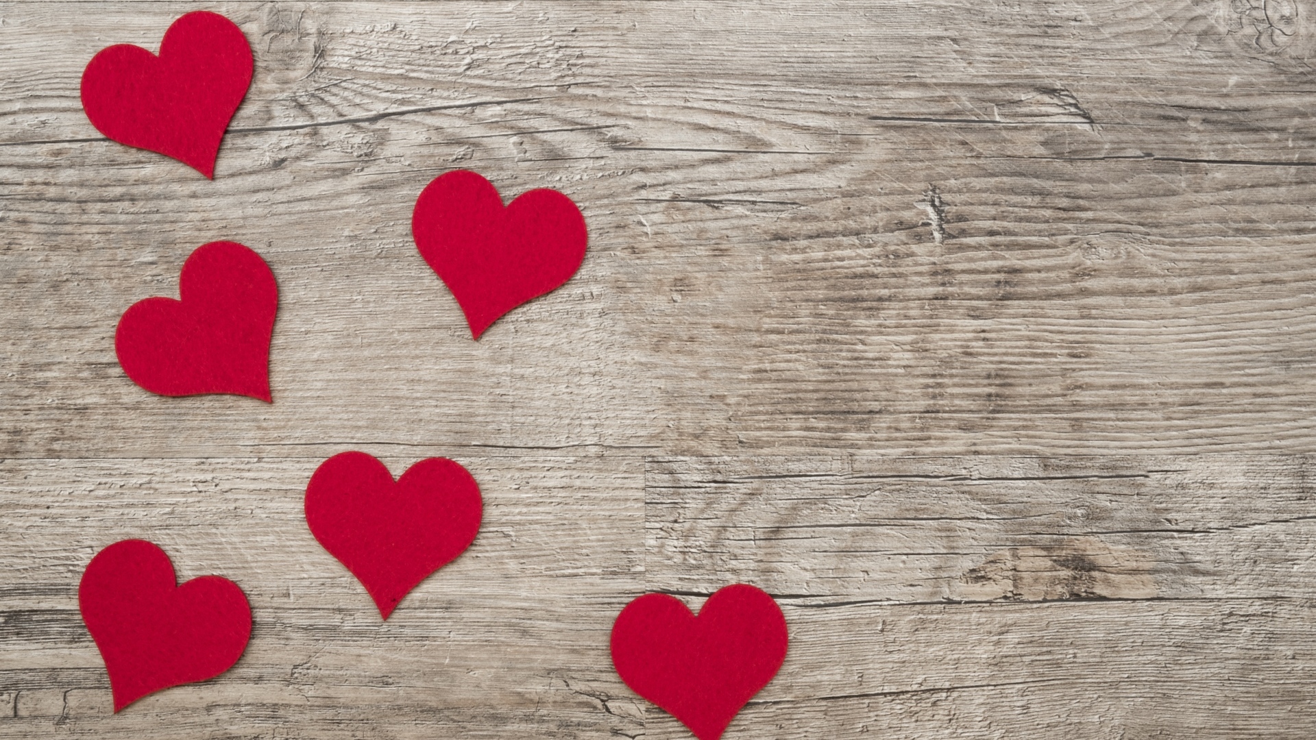 Маленькие красные сердечки на деревянном фоне