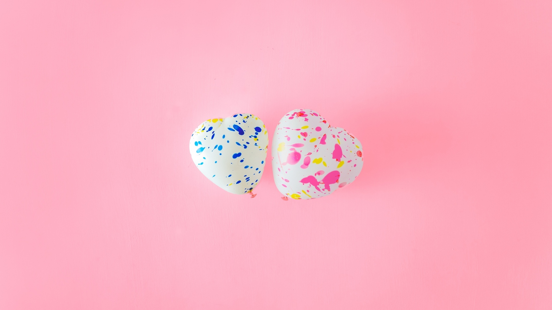 Два шарика в форме сердца на розовом фоне