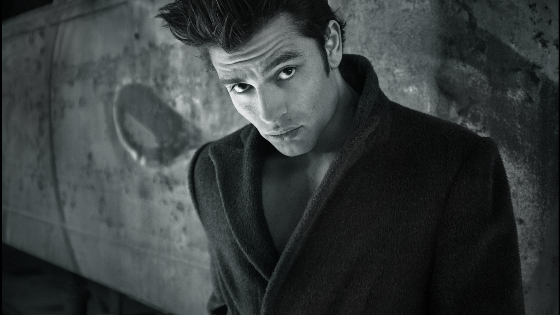 Красивый мужчина в черном пальто у стены