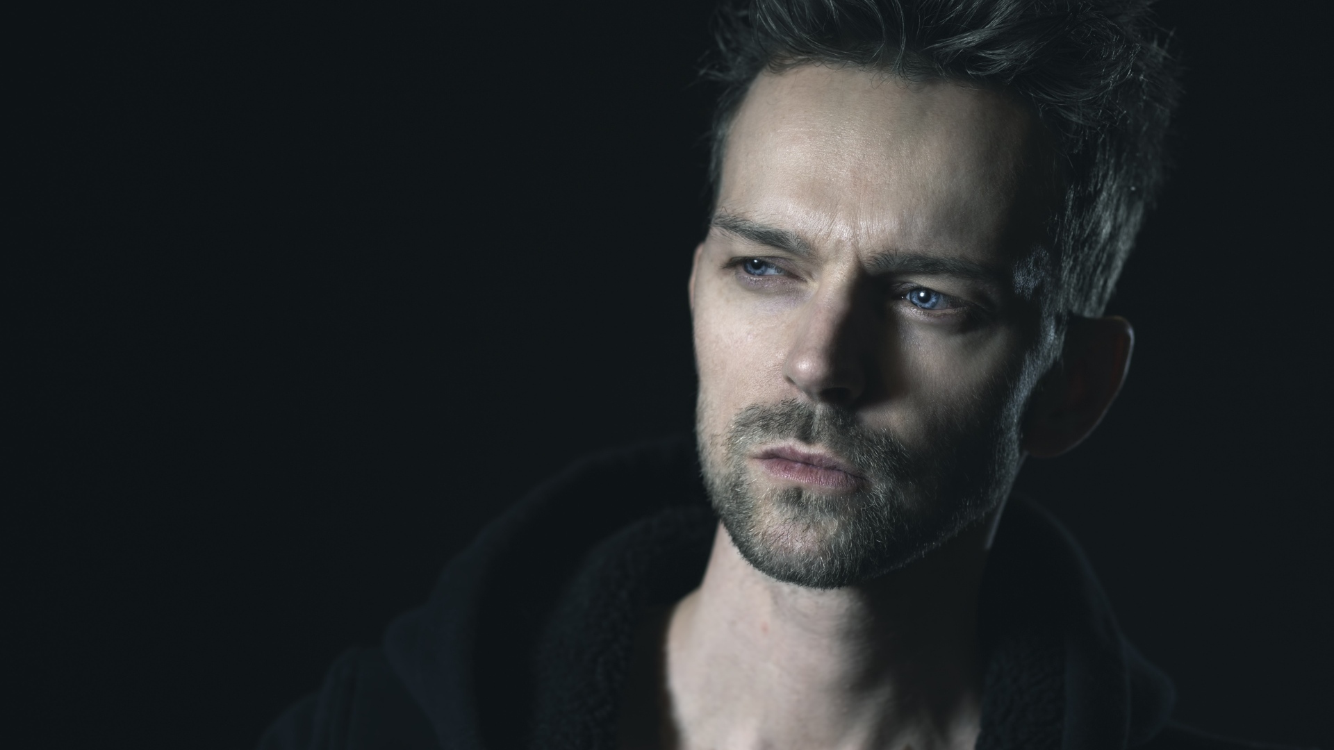 Серьезный голубоглазый мужчина на черном фоне