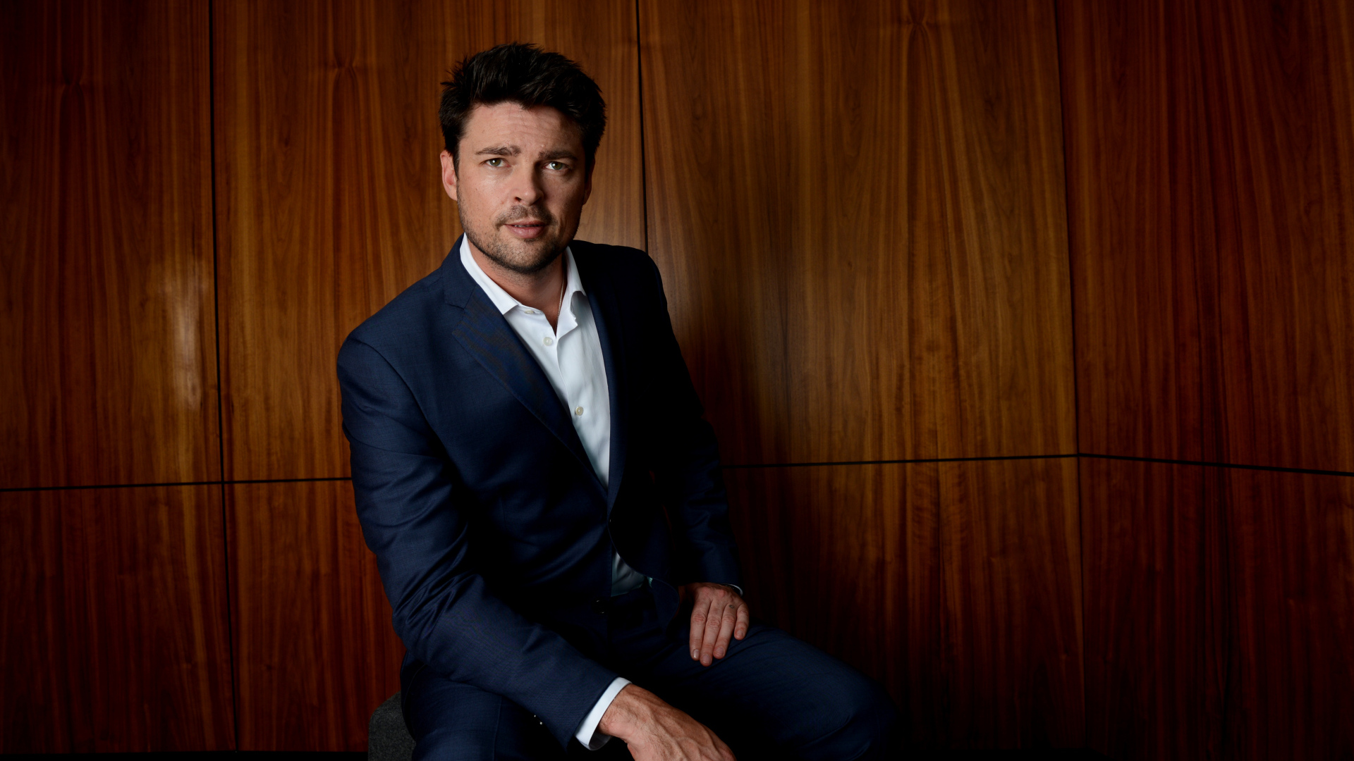 Актер Карл Урбан в костюме на фоне стены