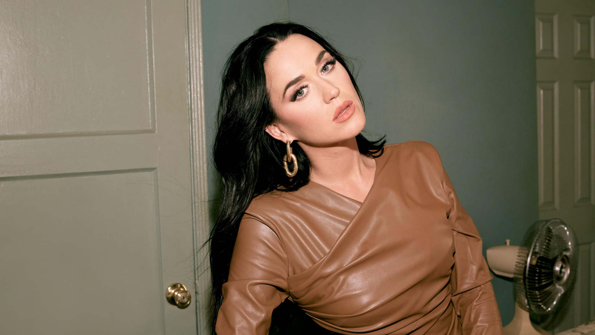 Длинноволосая брюнетка Кэти Перри стоит в комнате у двери