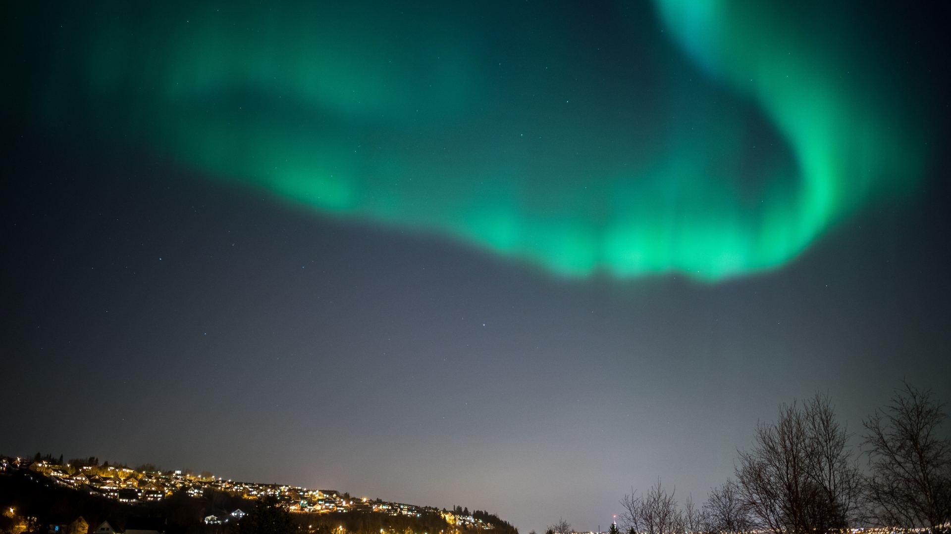 Зеленое полярное сияние в небе над ночным городом