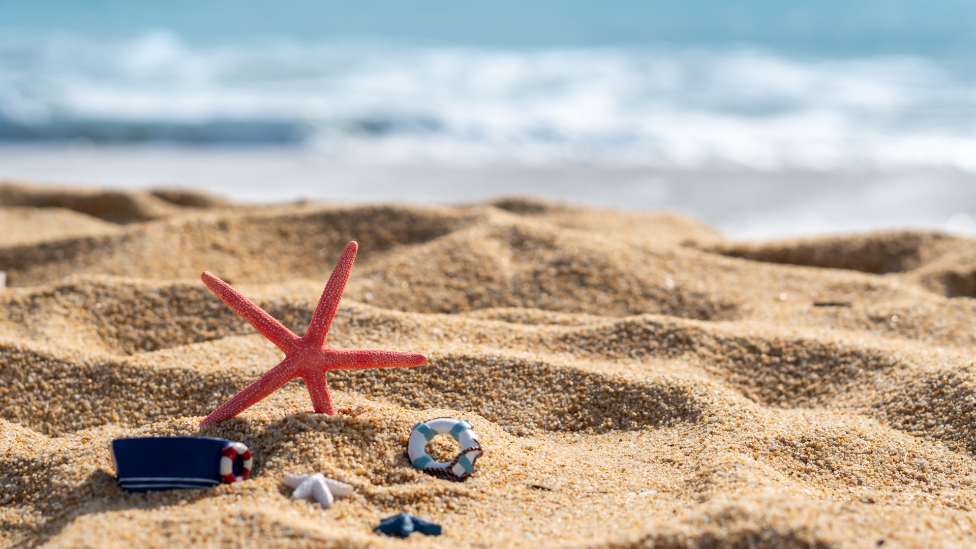 Красная морская звезда и игрушки на песке у моря летом