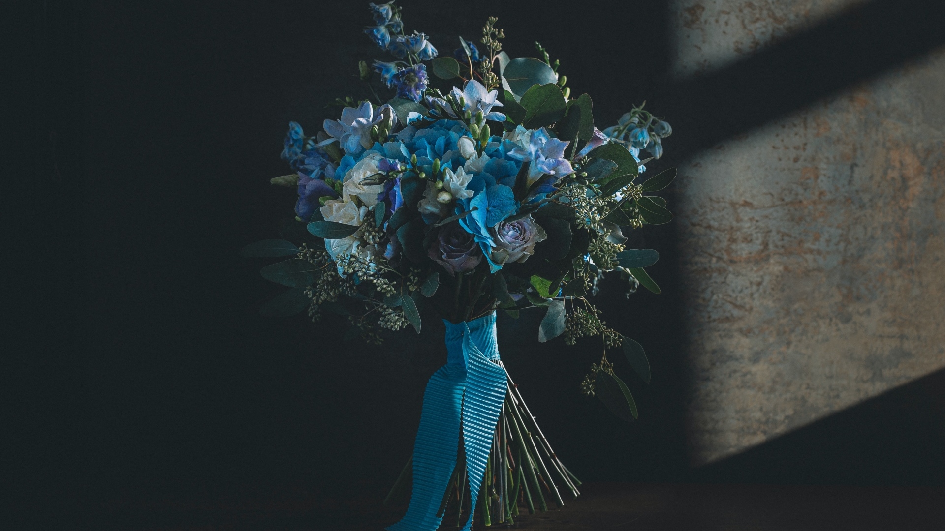 Красивый букет цветов с голубой лентой у стены