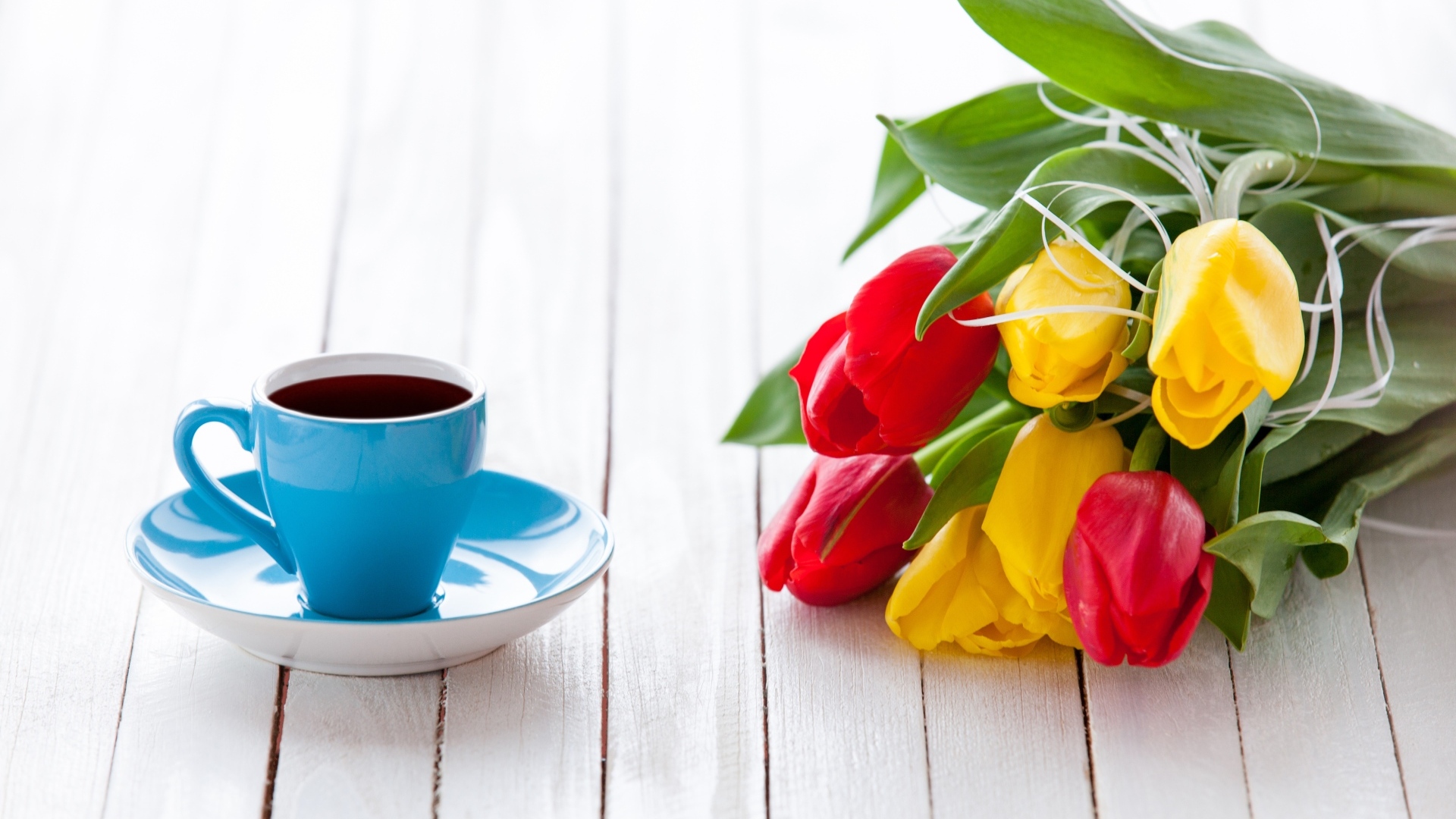 Голубая чашка на столе с букетом тюльпанов