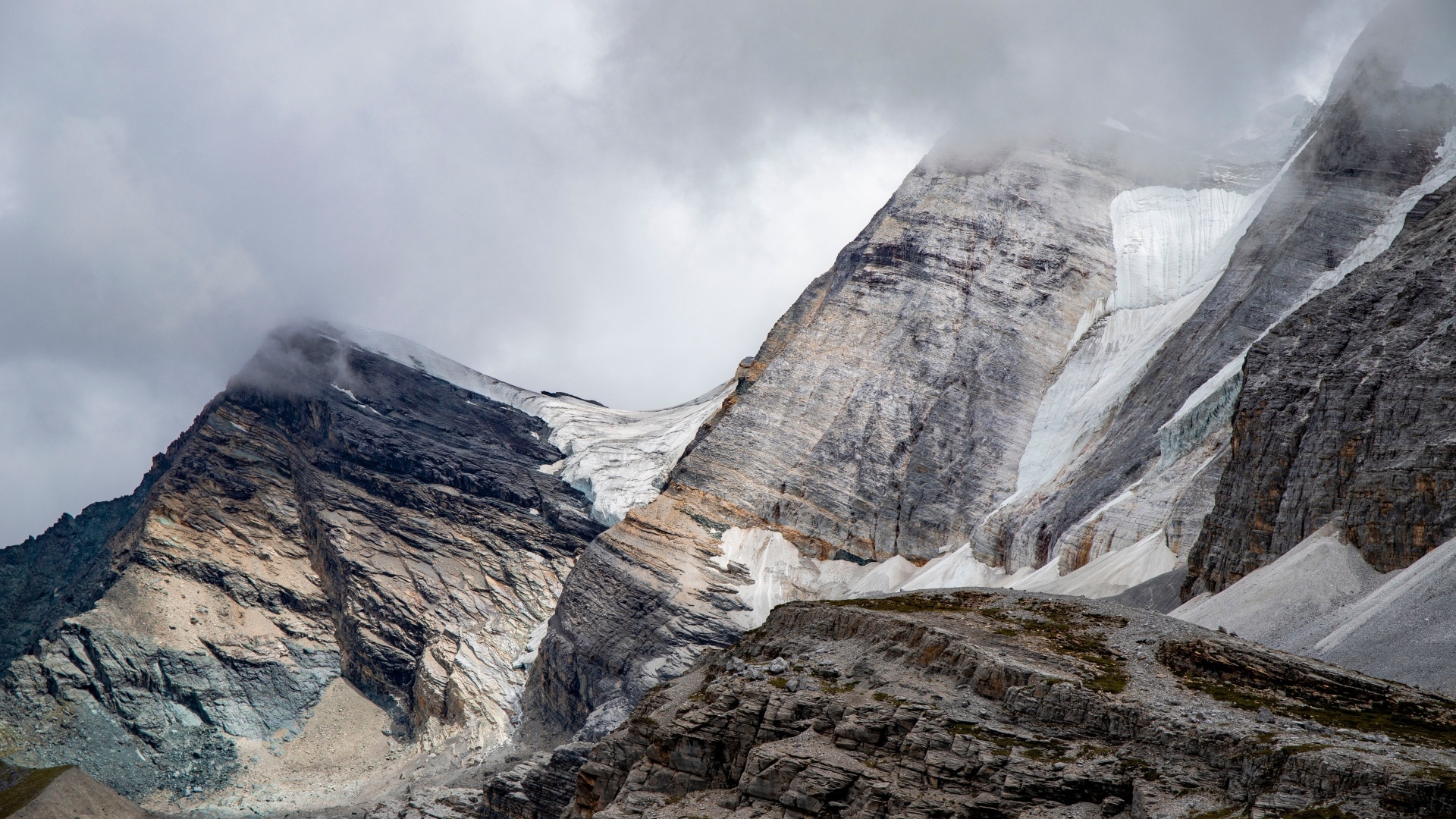 Высокие каменные горы в белых облаках