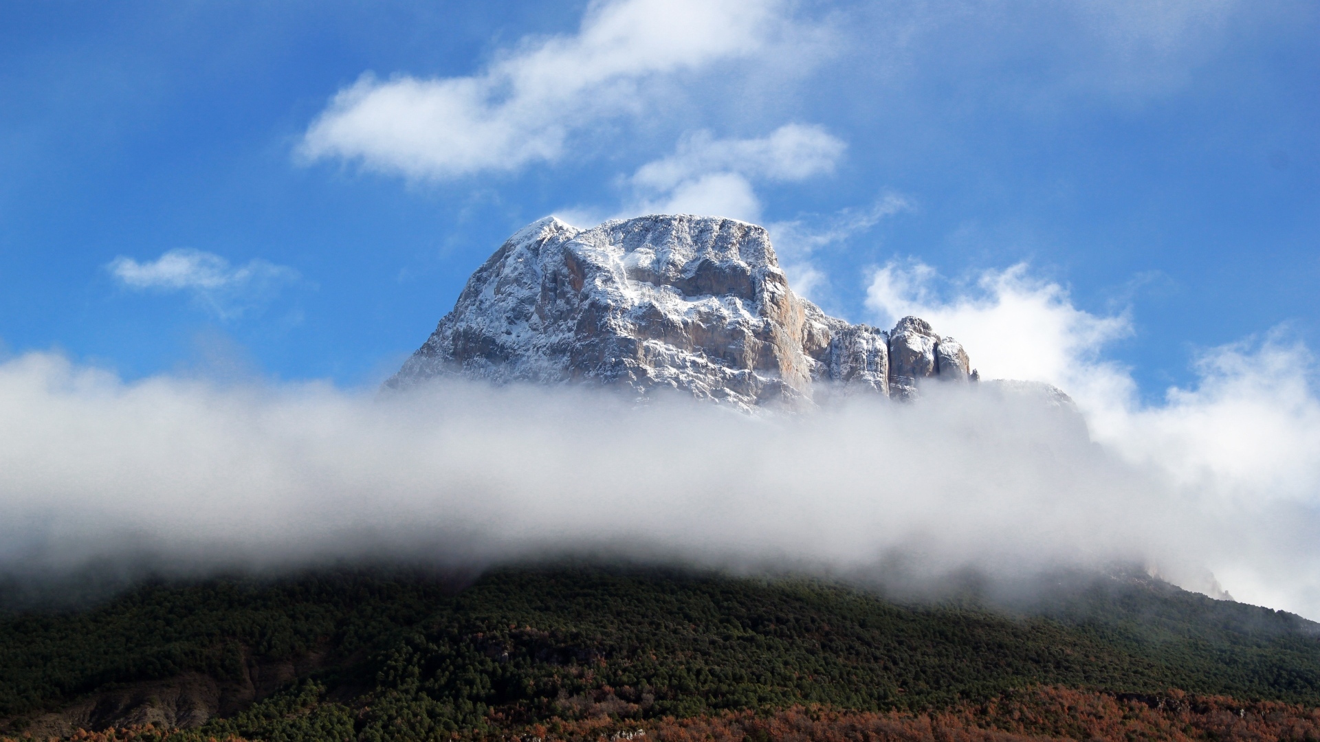 Заснеженная горная вершина в белых облаках