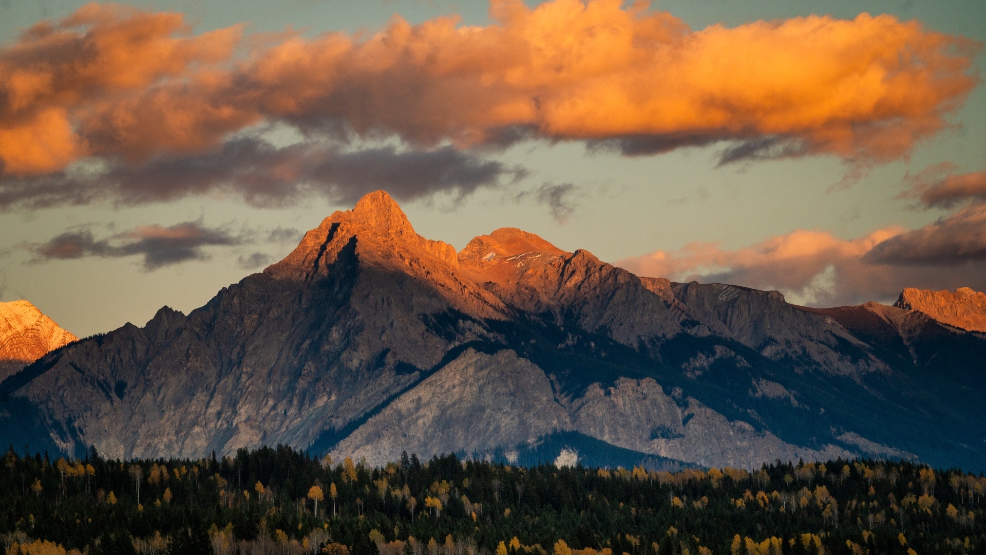 Солнце в облаках освещает вершину горы