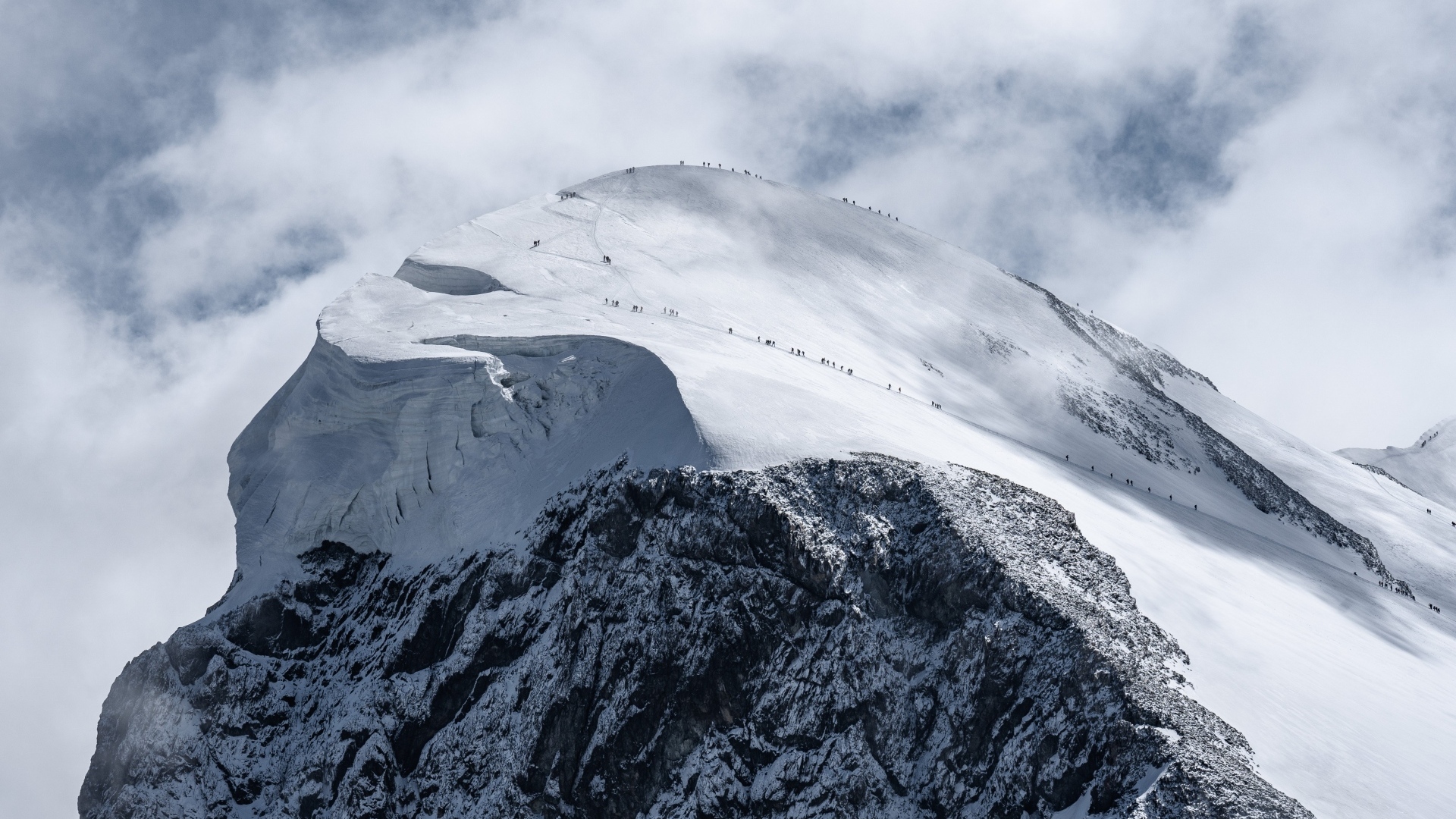 Вид на заснеженную вершину горы под белыми облаками
