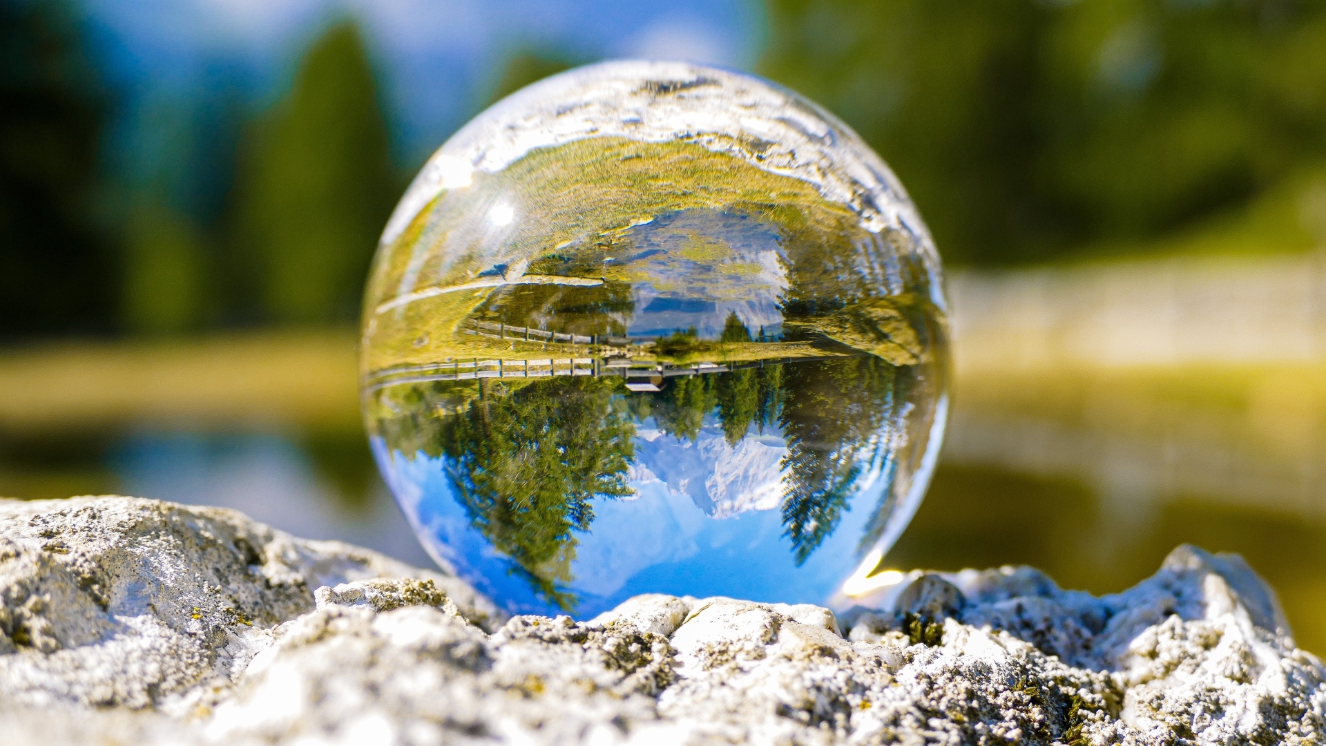 Стеклянный шар стоит на камне у воды