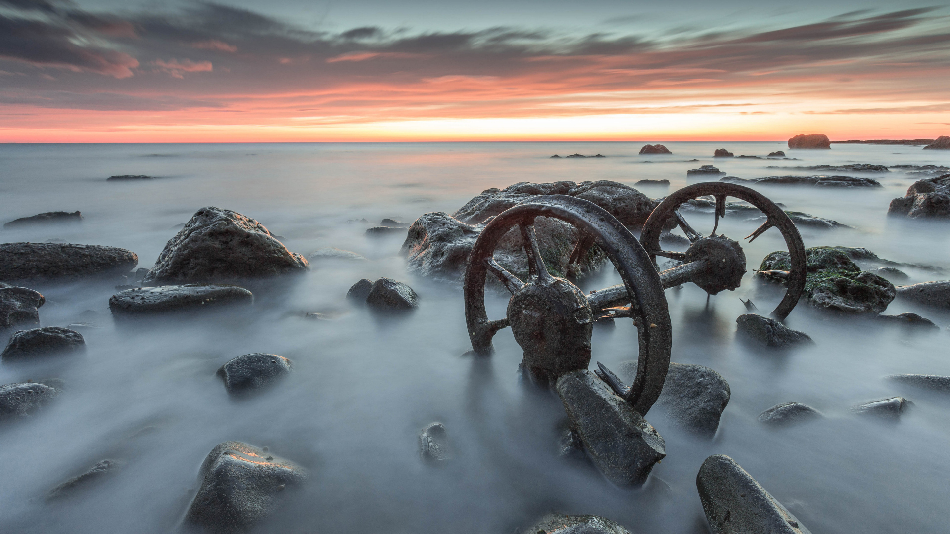Старые колеса лежат в воде с камнями