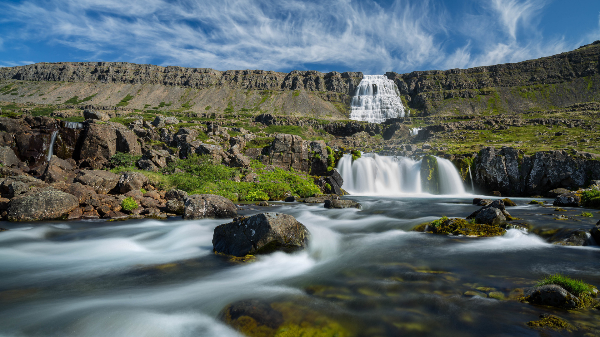 Водопад стекает с гор на фоне красивого голубого неба Исландии