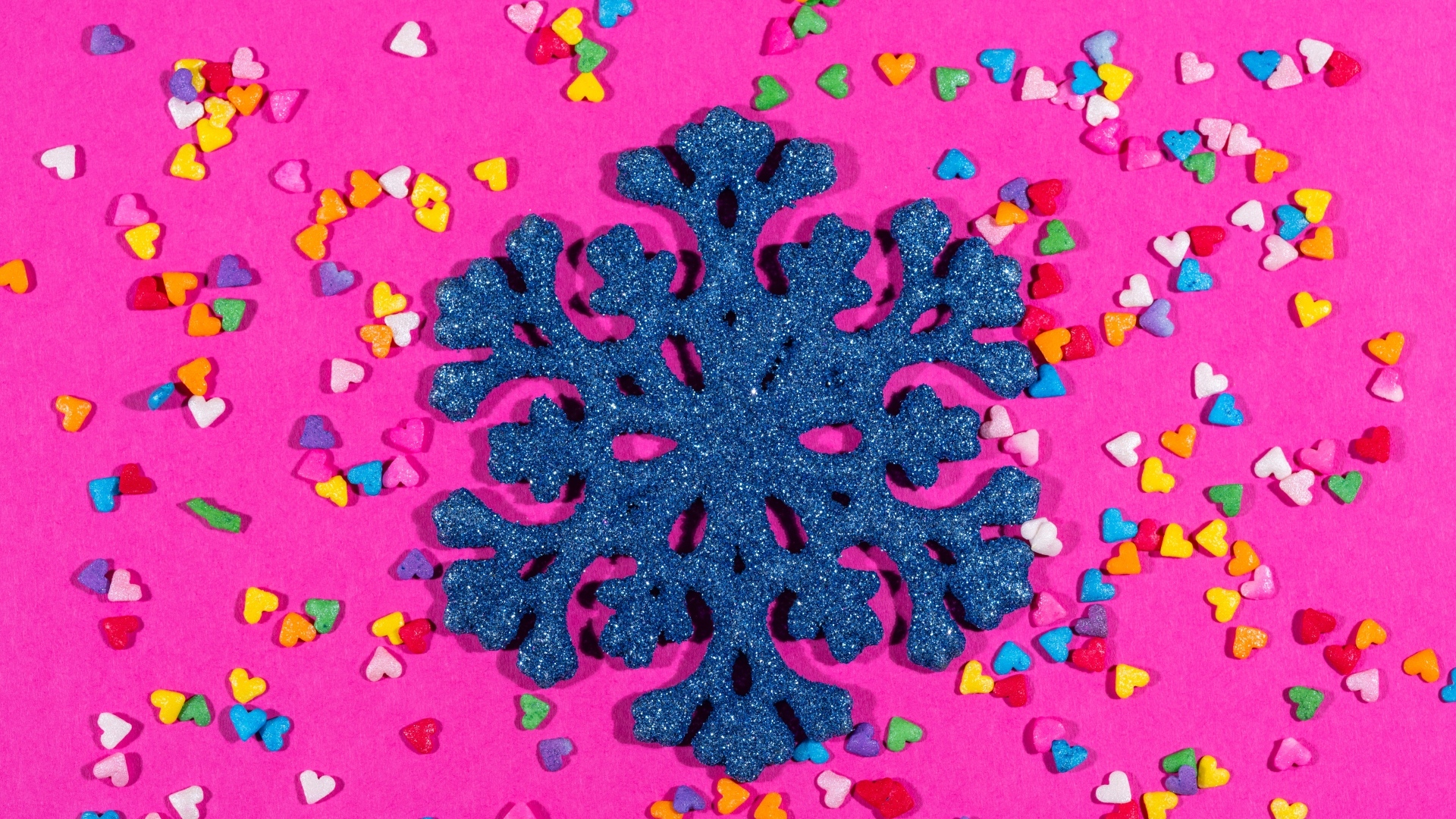 Большая синяя снежинка на розовом фоне с сердечками