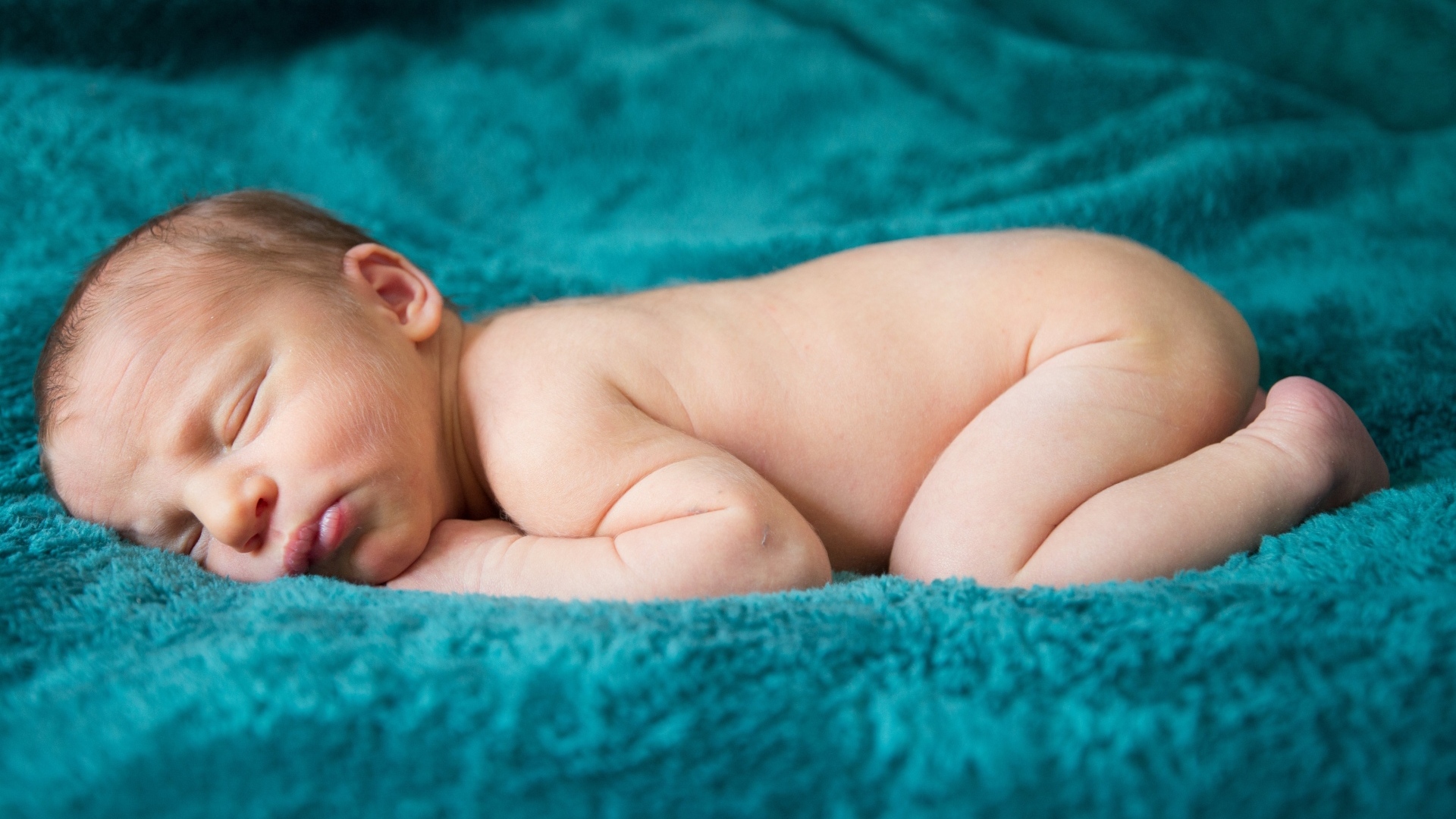 Грудной ребенок спит на синем пледе