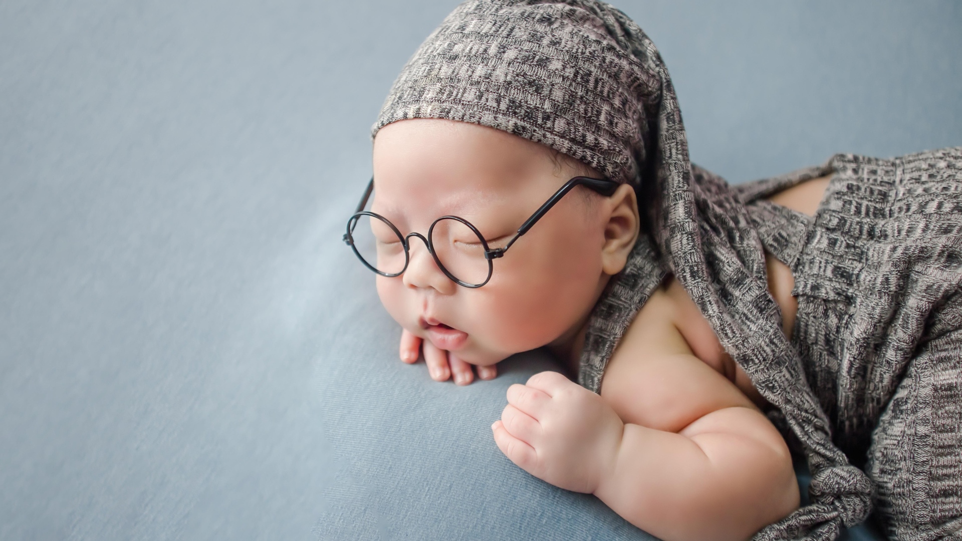 Забавный малыш в очках одет в серый костюм