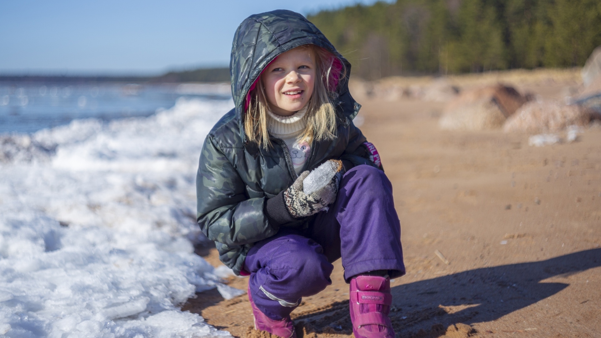 Девочка сидит у замерзшего озера 