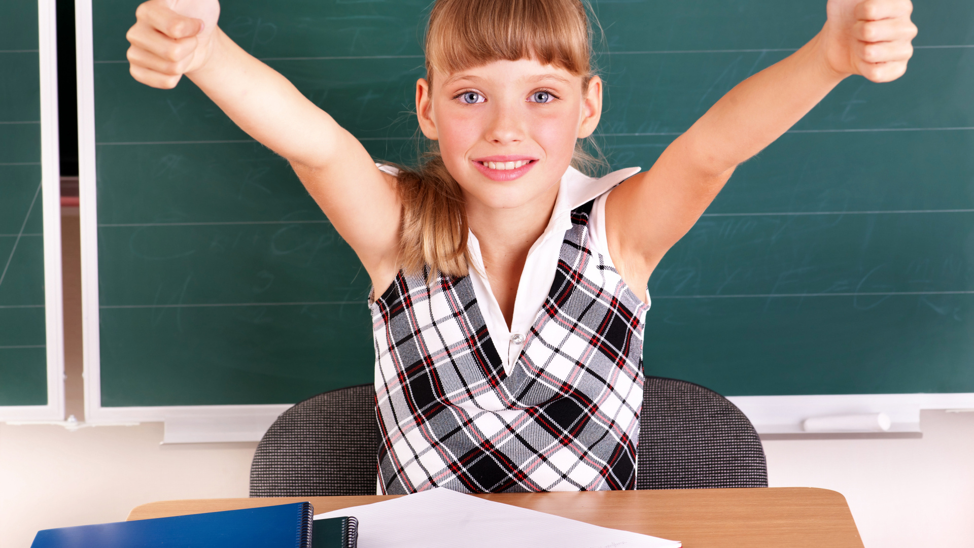 Маленькая девочка школьница в классе за партой 