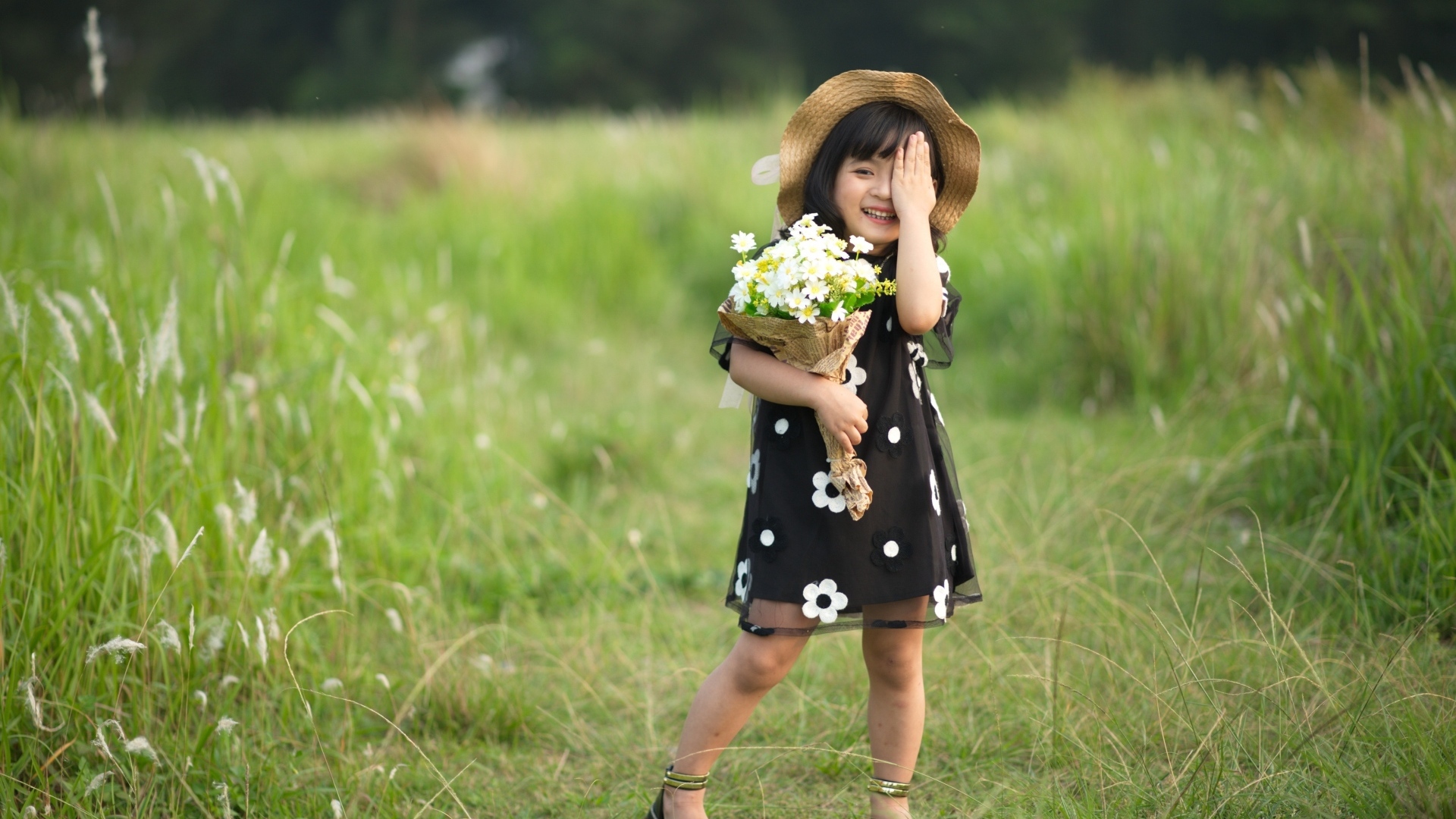 Маленькая девочка с букетом цветов на зеленой траве