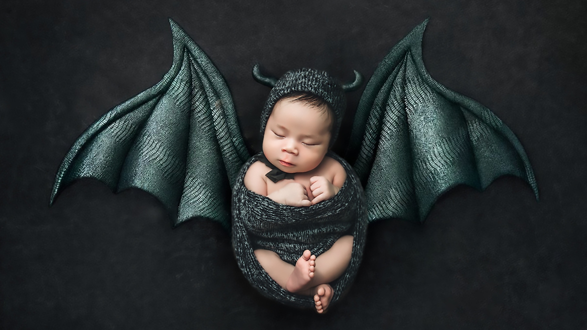 Маленький спящий ребенок с крыльями на Хэллоуин