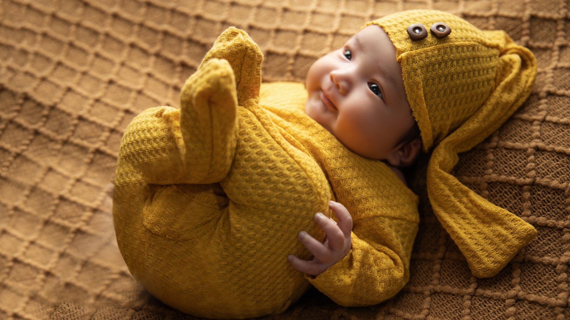 Новорожденный ребенок в желтом костюме 