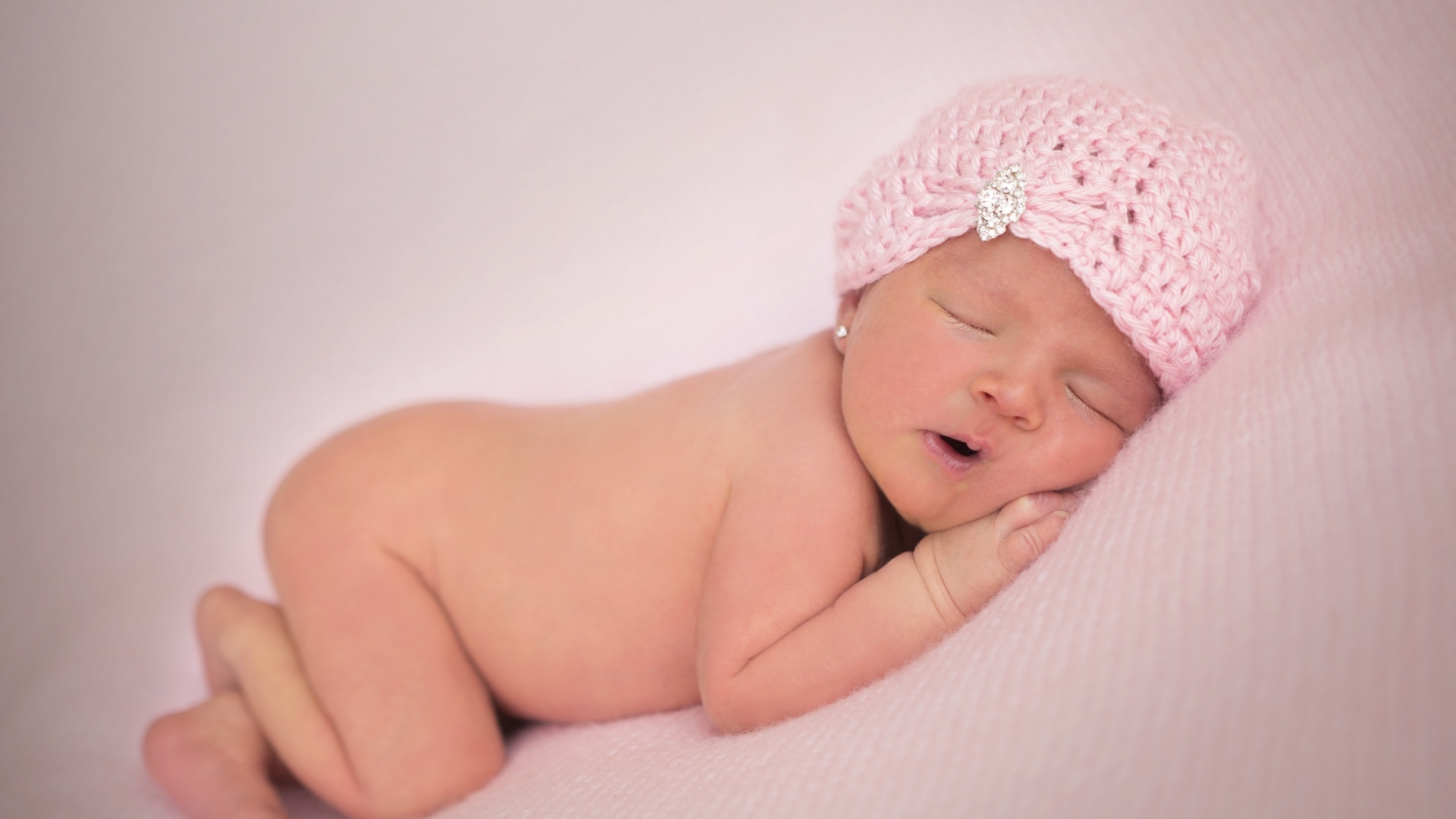 Розовая шапка на голове новорожденной девочки