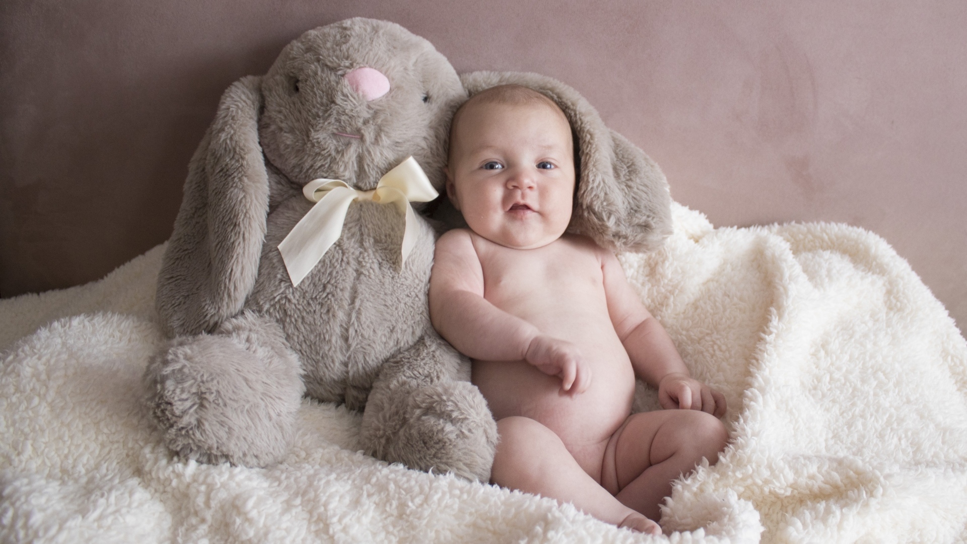 Улыбающийся малыш с игрушечным зайцем