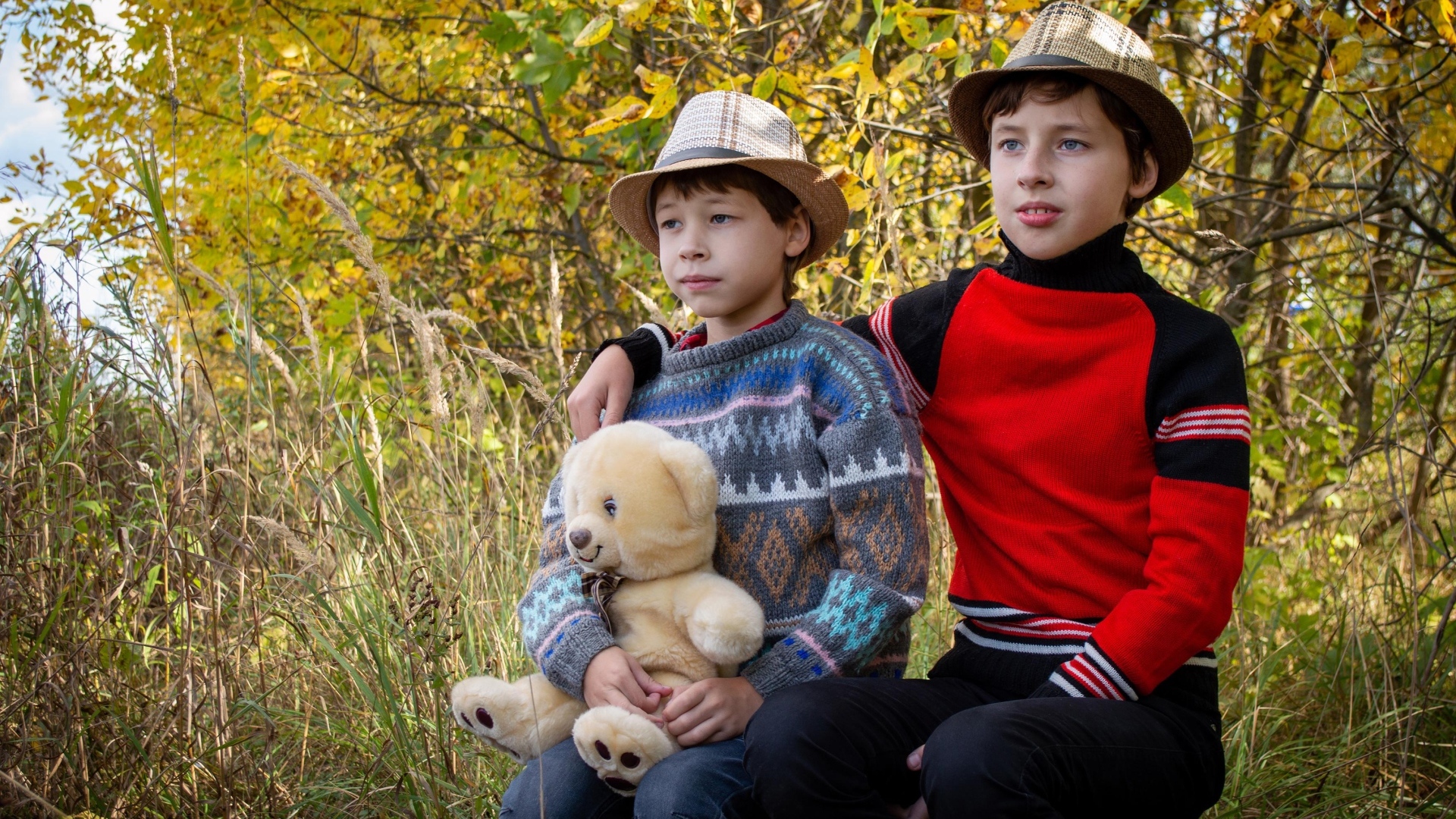 Два мальчика с игрушкой сидят у дерева