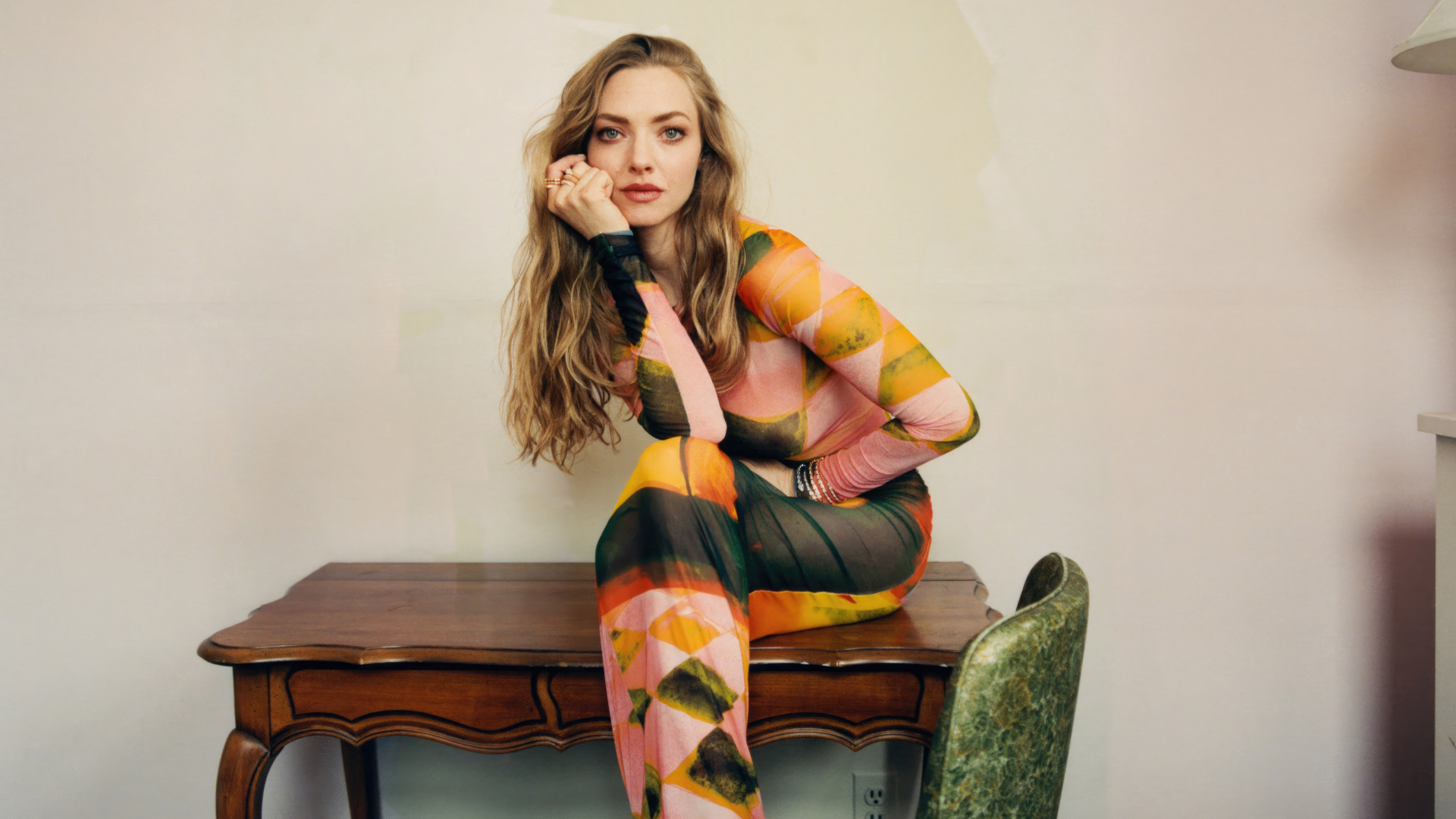 Актриса Аманда Сайфред в платье сидит на столе