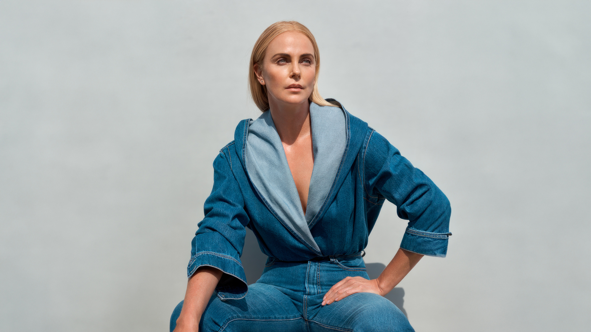 Актриса Шарлиз Терон в джинсовом костюме на сером фоне