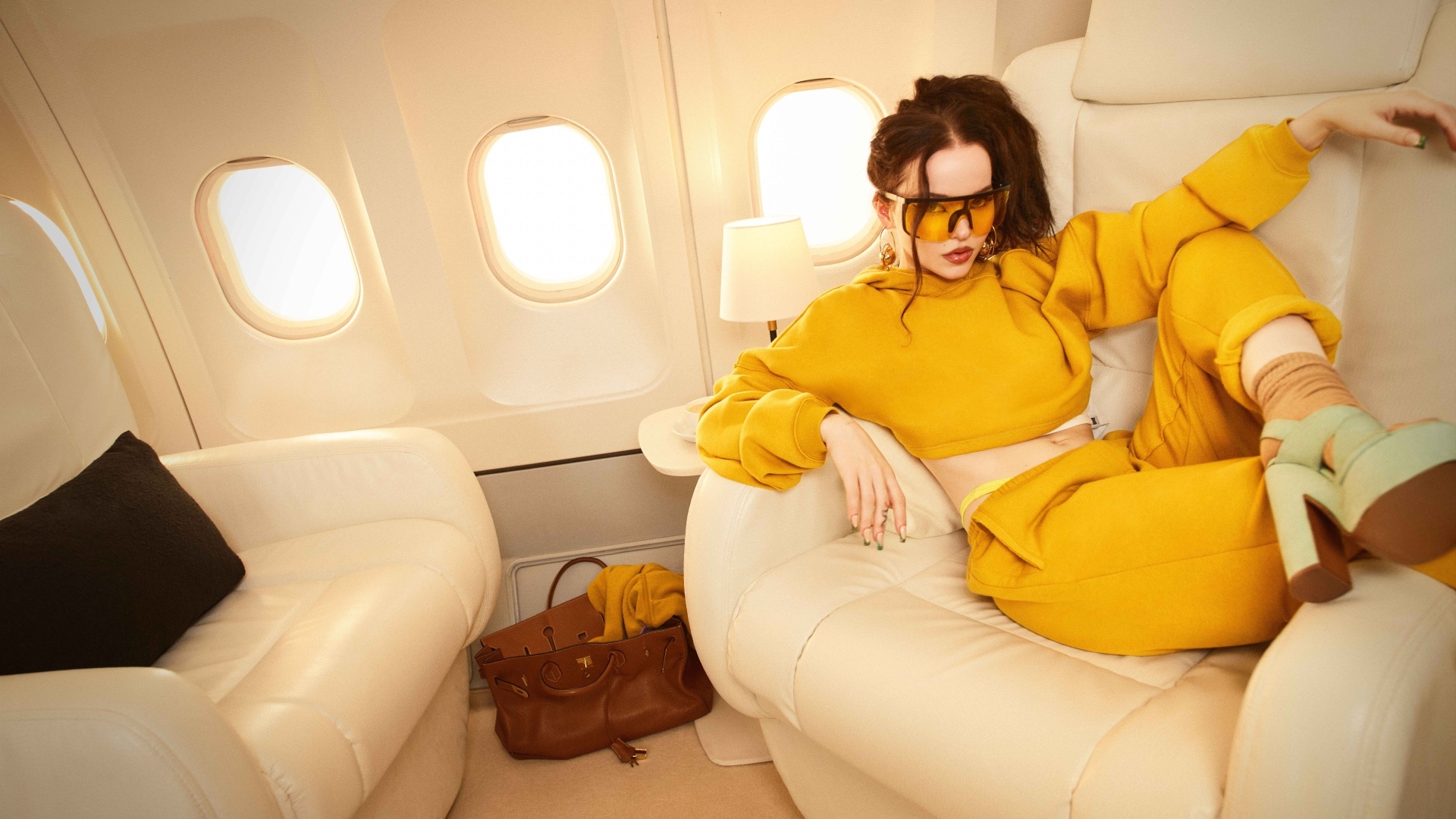 Актриса Дав Кэмерон в желтом костюме в самолете