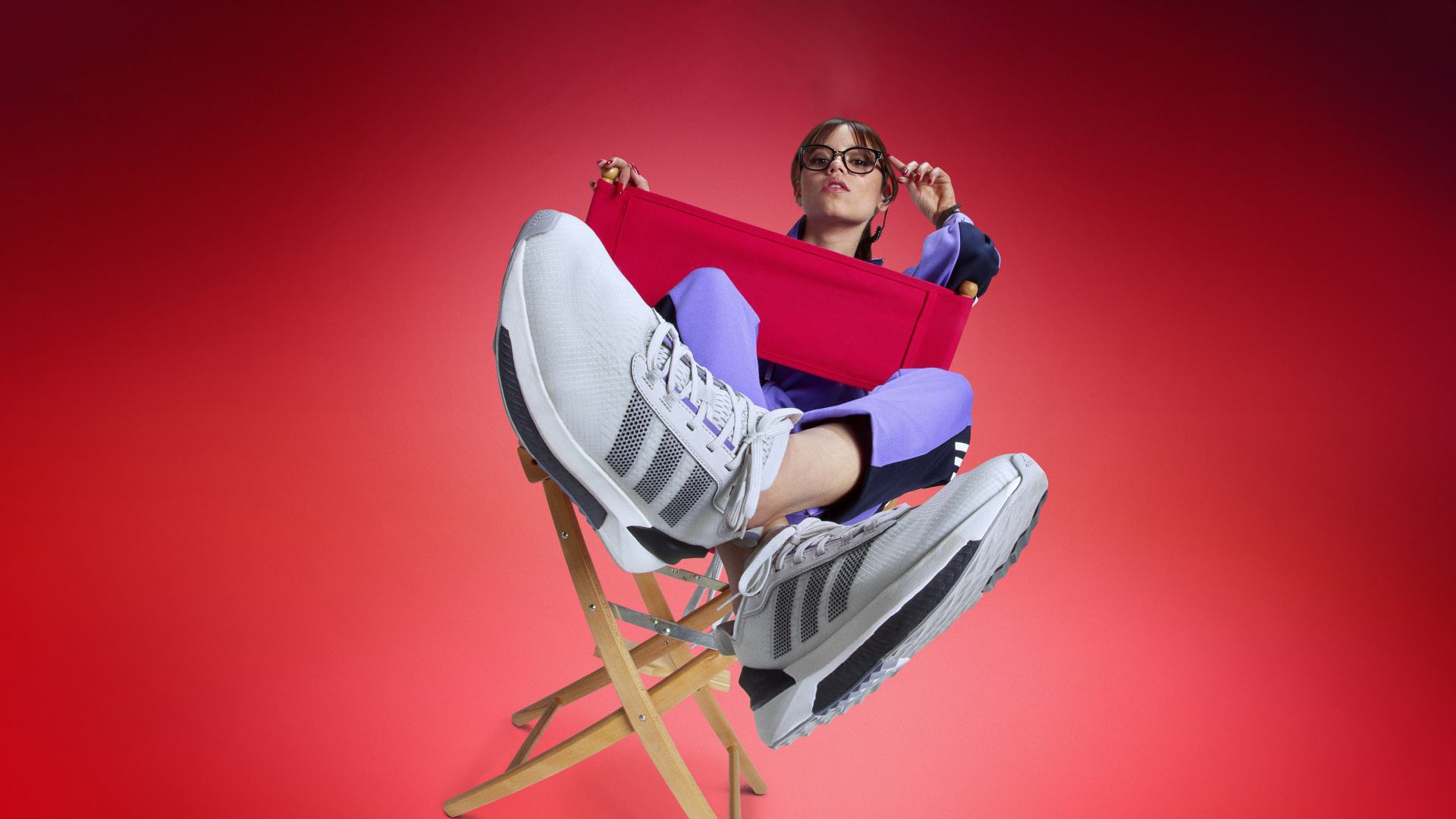 Актриса Дженна Ортега в кроссовках адидас сидит на стуле