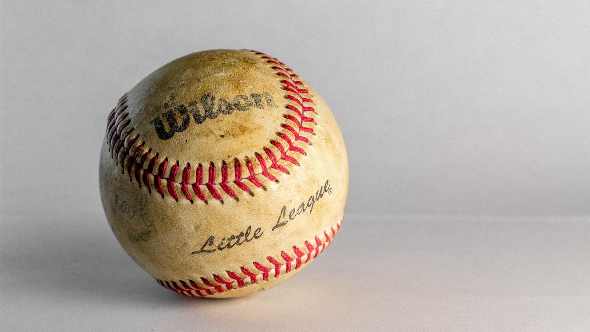 Старый бейсбольный мяч на сером фоне