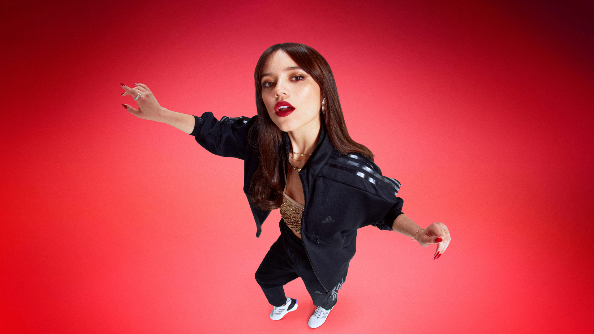 Молодая девушка актриса Дженна Ортега в спортивном костюме на красном фоне