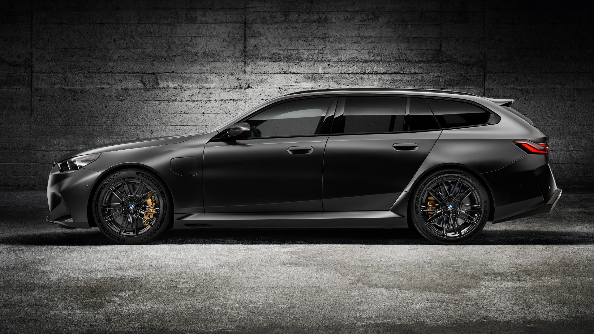 Вид сбоку на черный автомобиль BMW M5 Touring 2024 года