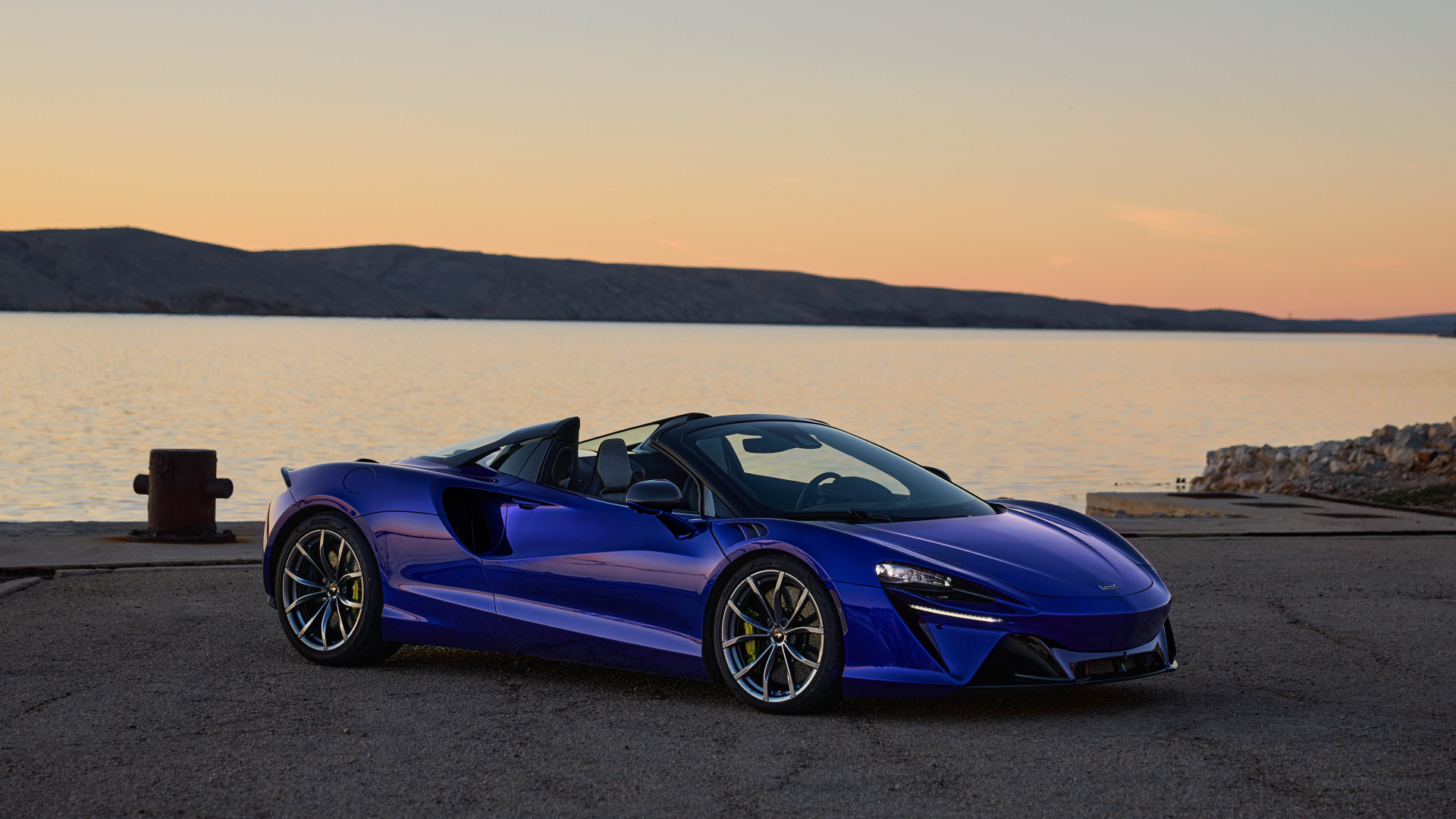 Синий быстрый автомобиль McLaren Artura Spider у воды