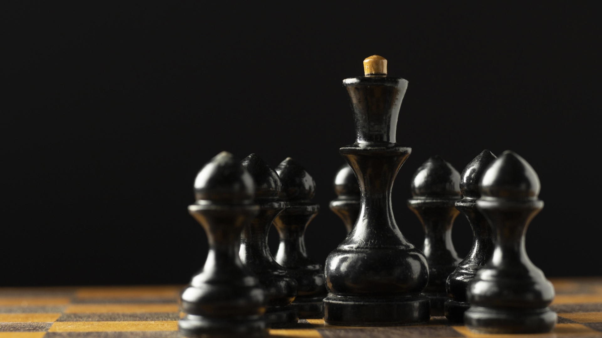 Черные шахматные фигуры на доске на черном фоне