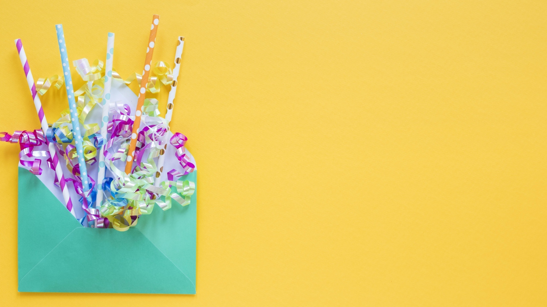 Конверт с трубочками и лентами на желтом фоне