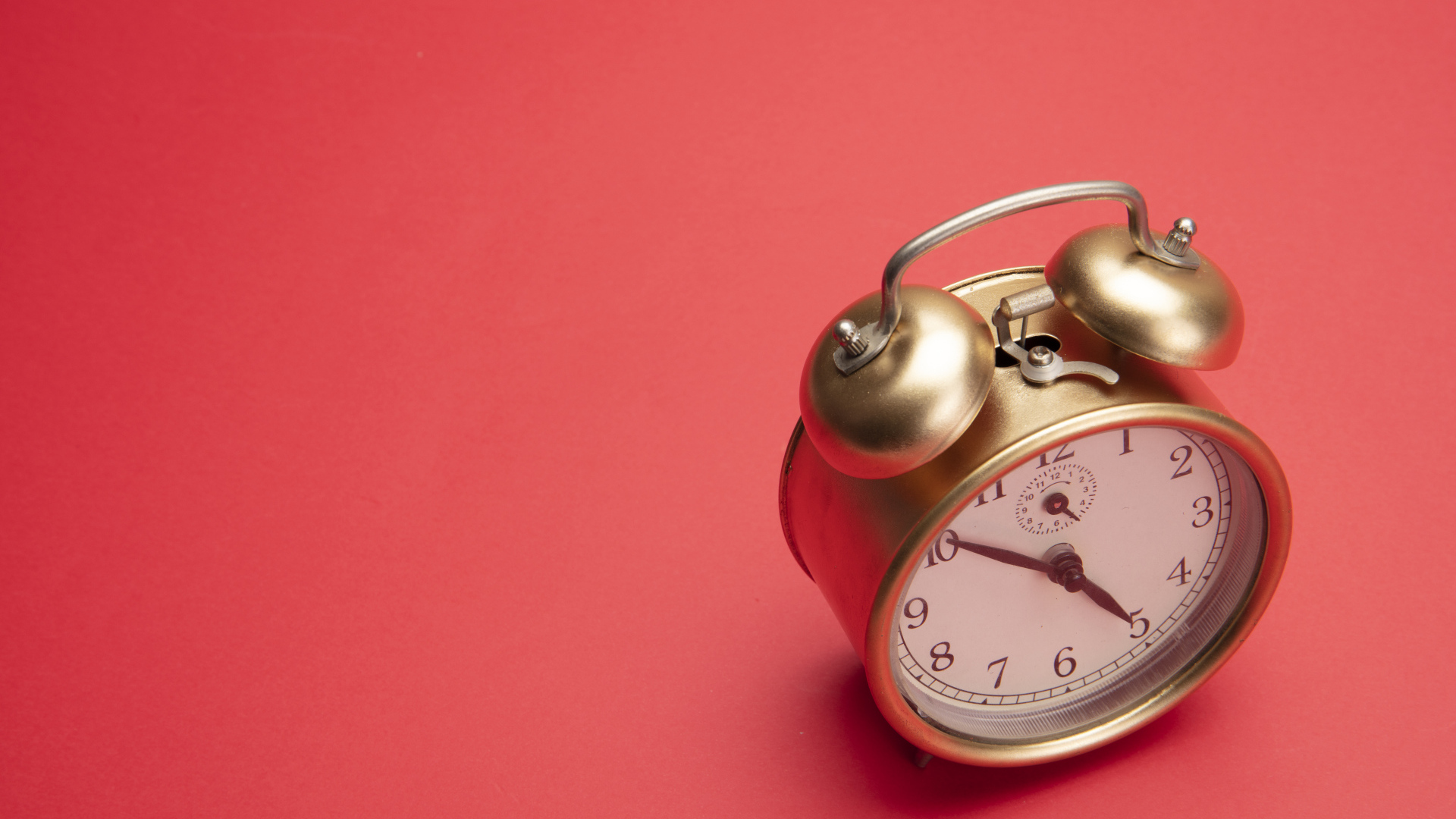 Золотой будильник на красном фоне