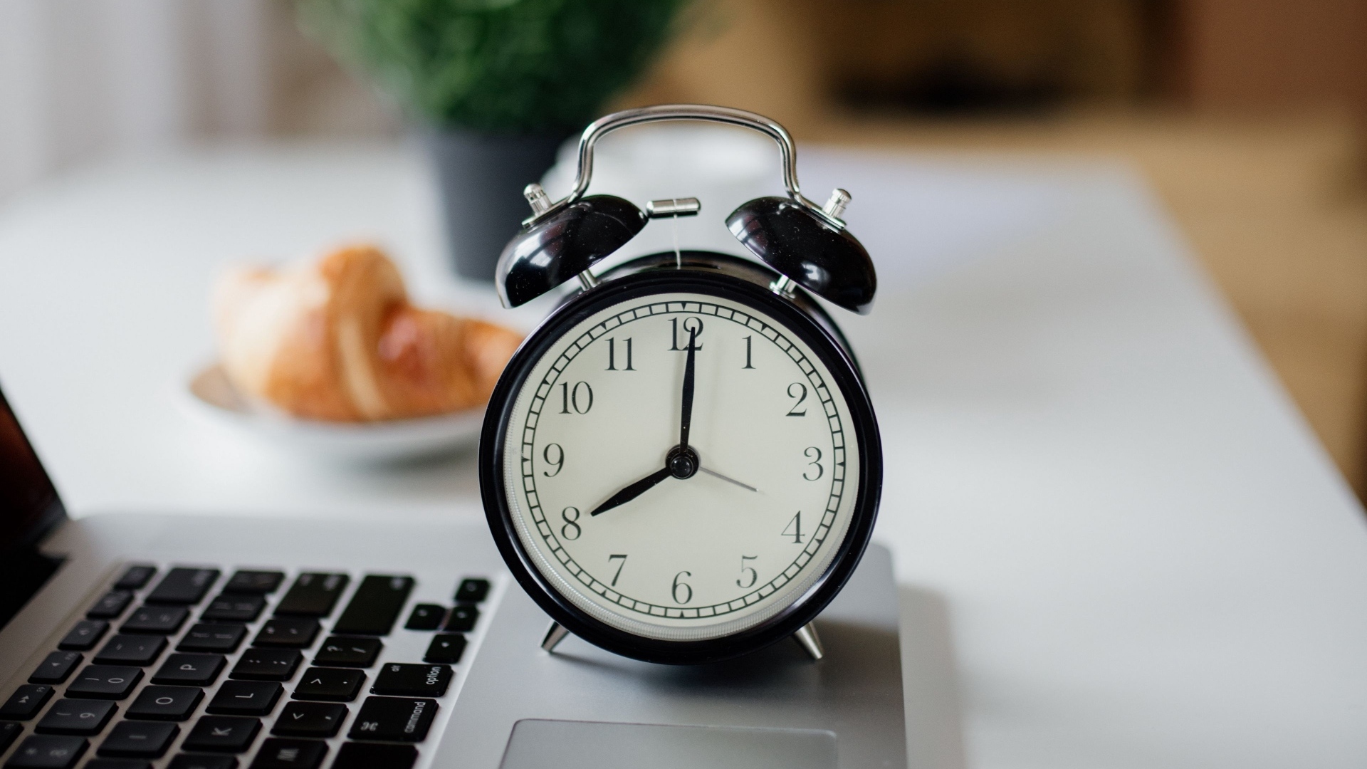 Большой черный будильник на столе у ноутбука