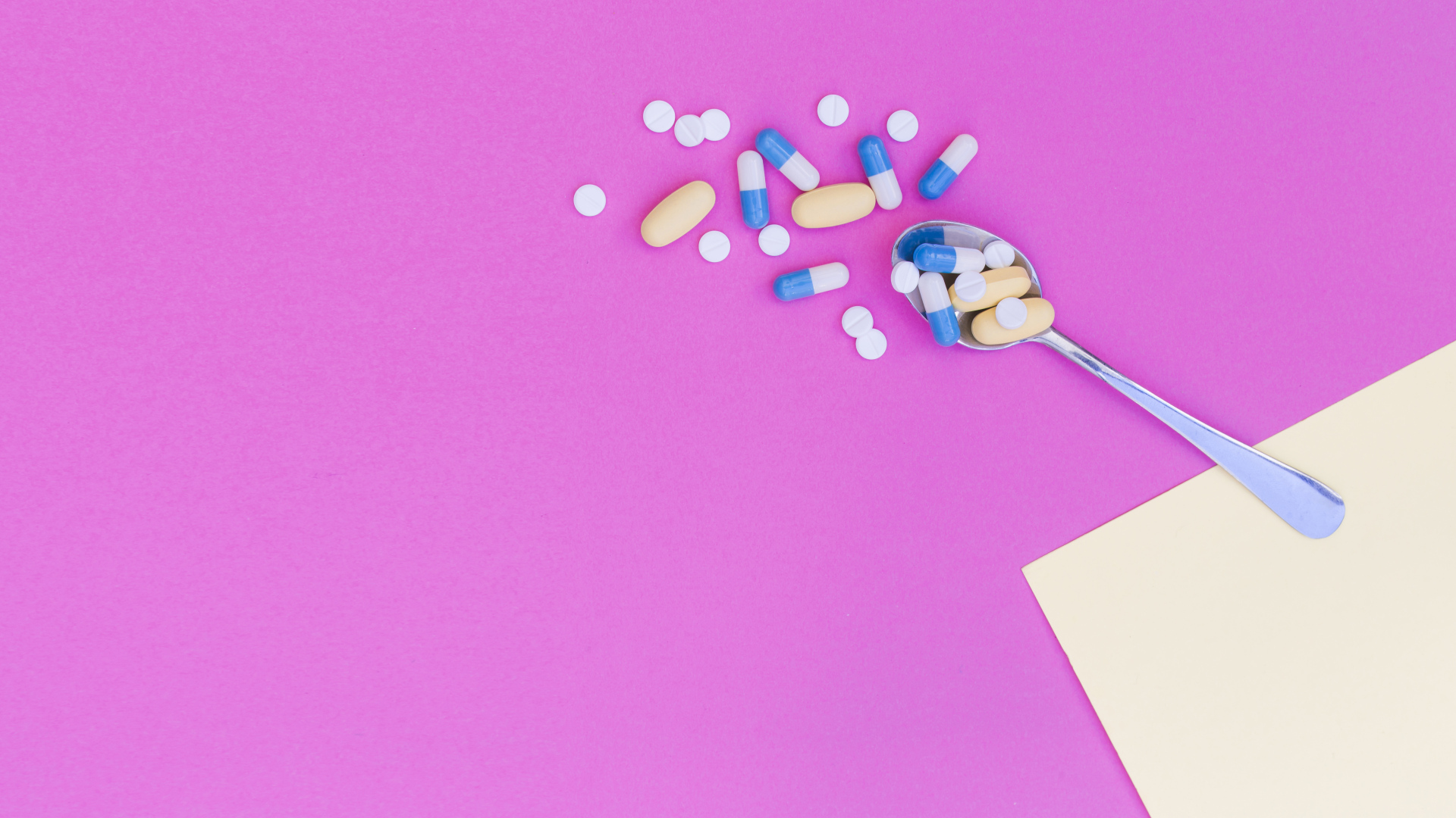 Таблетки с ложкой на розовом фоне
