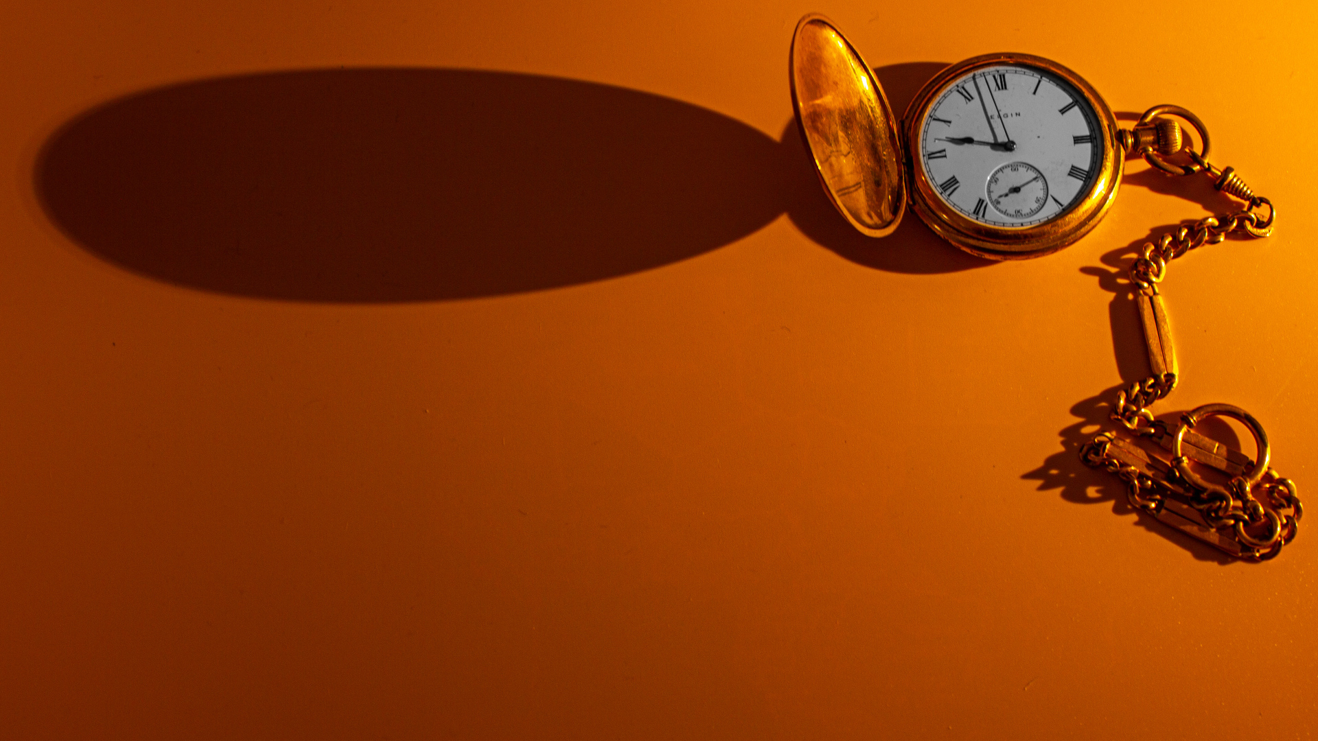 Тень от карманных часов на оранжевом фоне
