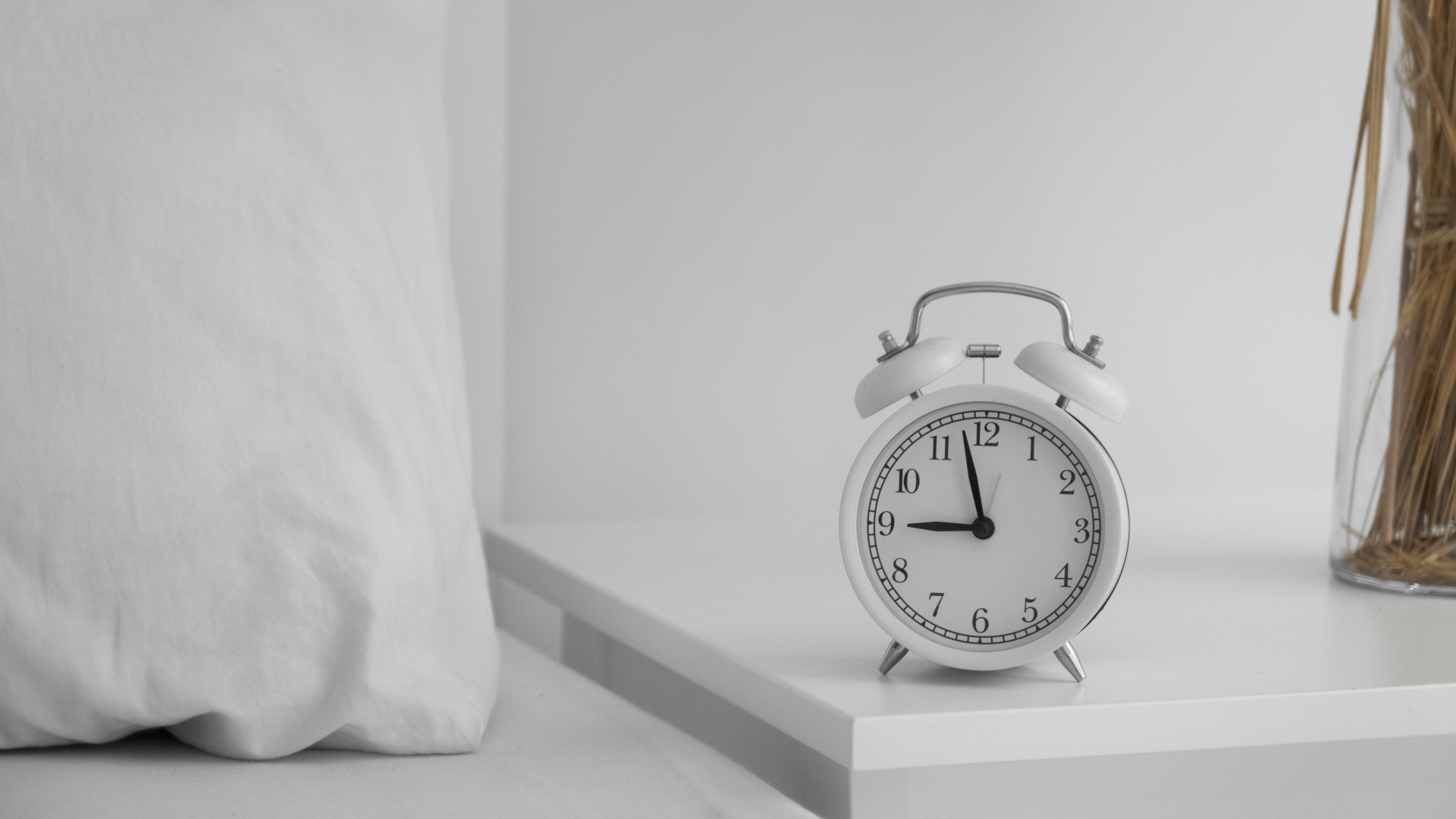 Будильник стоит на тумбочке у кровати 