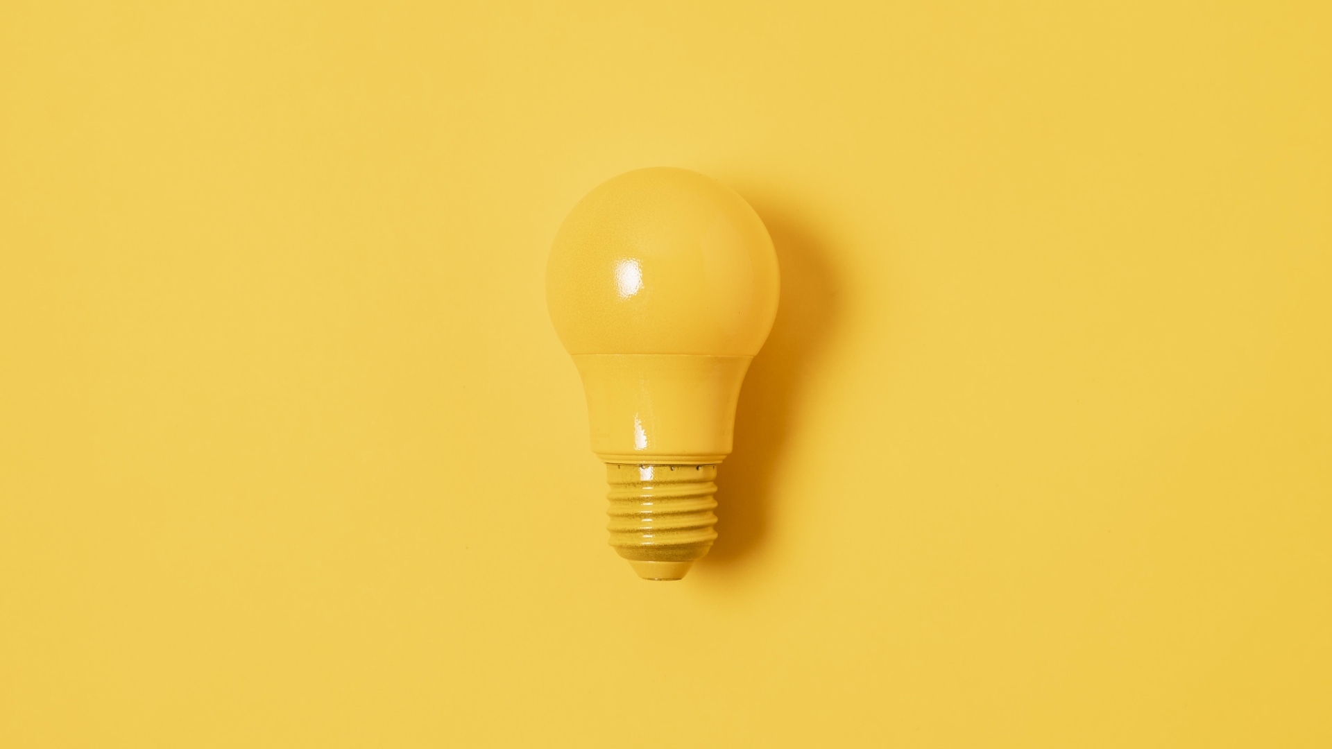 Желтая лампочка накаливания на желтом фоне
