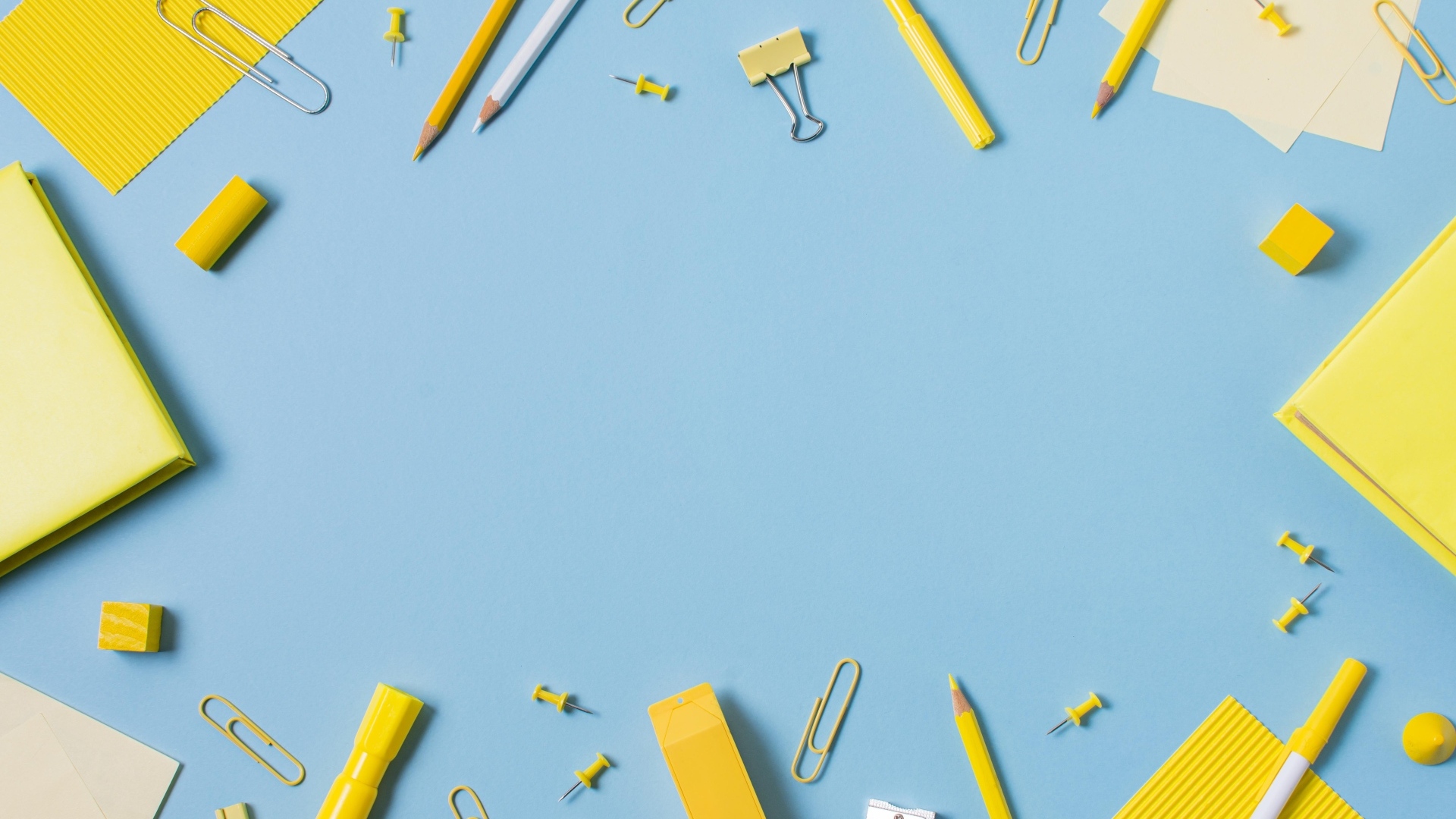 Желтые канцелярские предметы на голубом столе