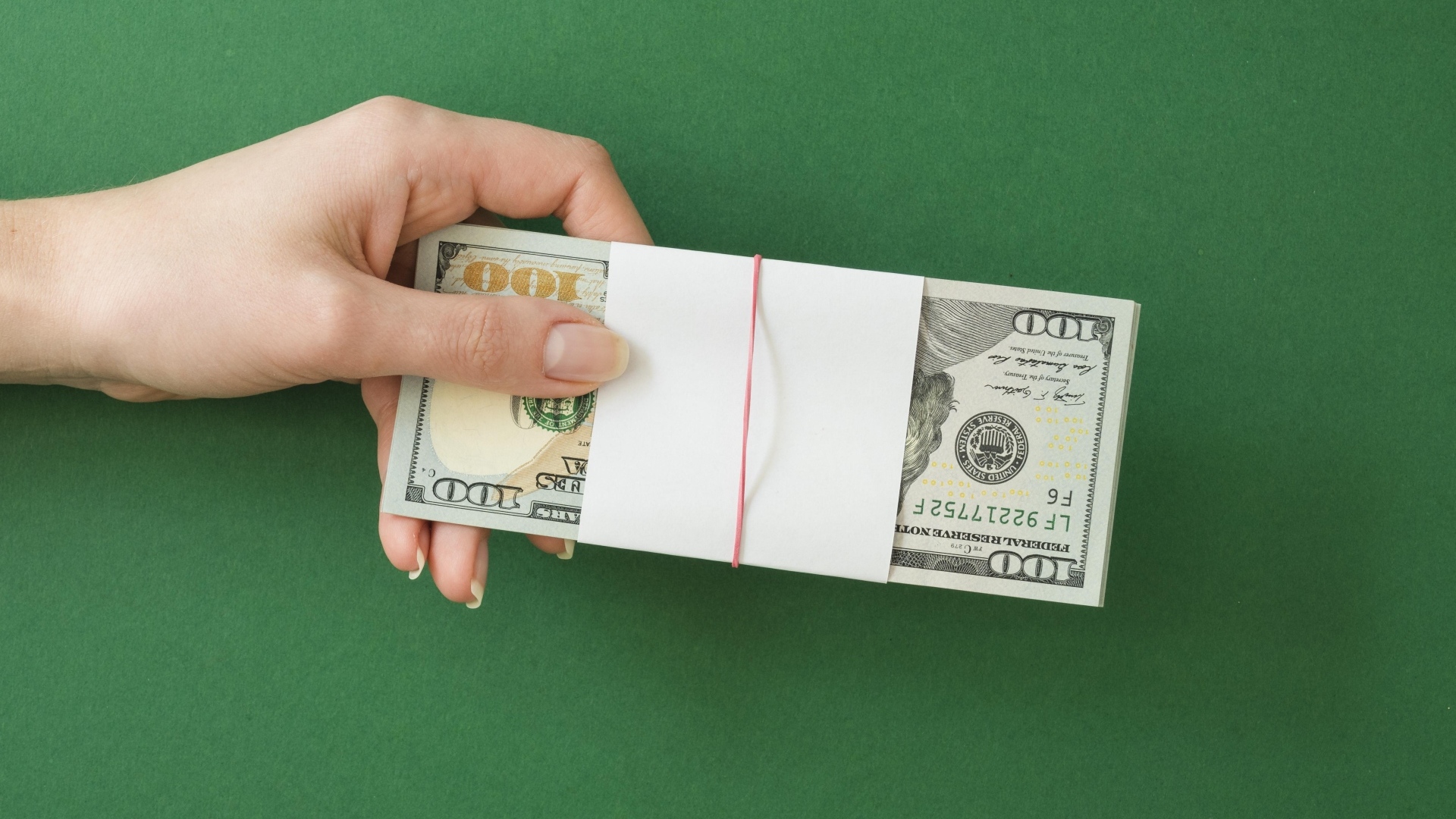 Пачка денег в руке у девушки на зеленом фоне