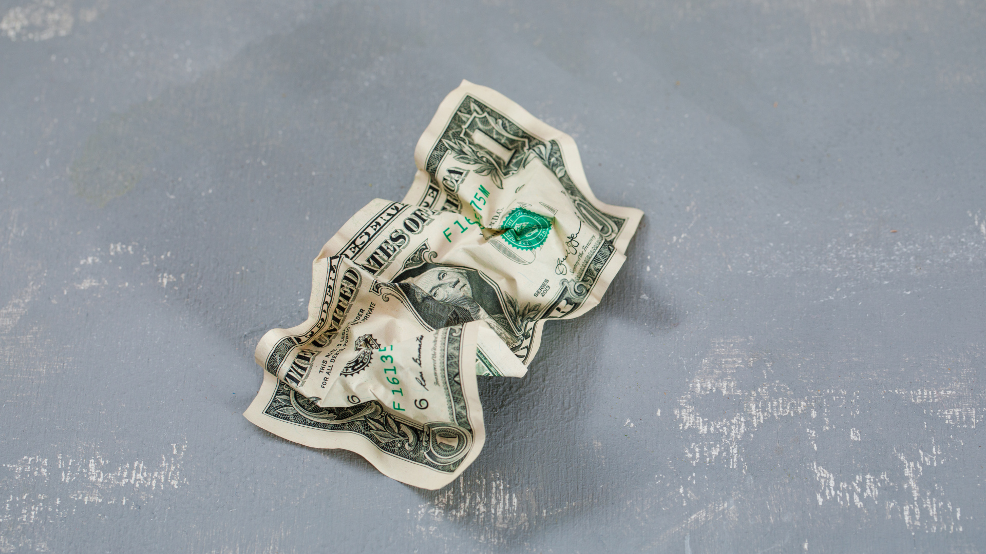 Смятая купюра один доллар на сером столе